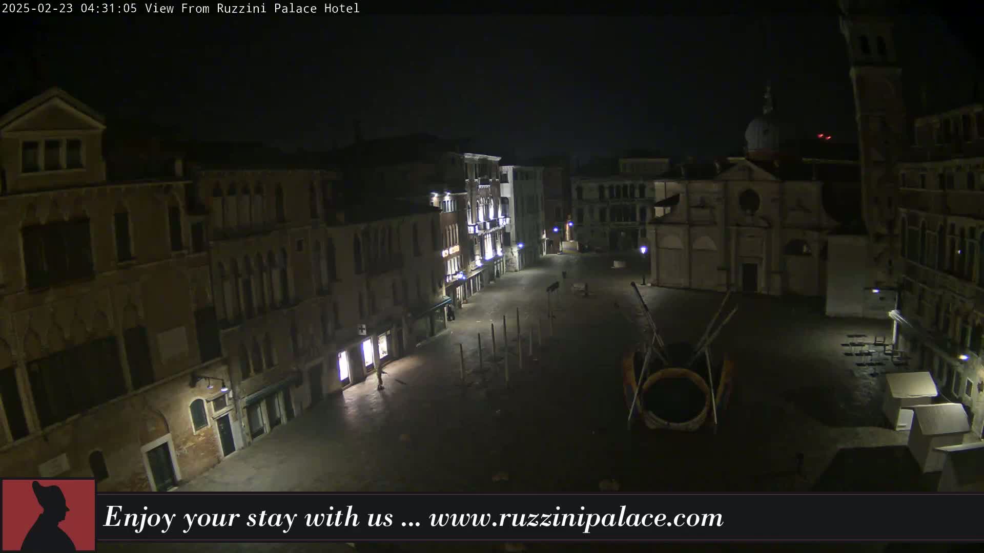 A nighttime, aerial view of a deserted Venetian square, surrounded by old buildings under a clear, dark sky.