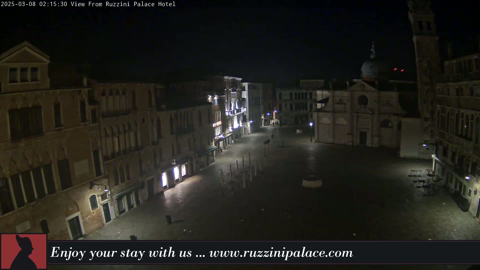 A nighttime view of a deserted plaza in Venice, Italy, surrounded by old buildings.