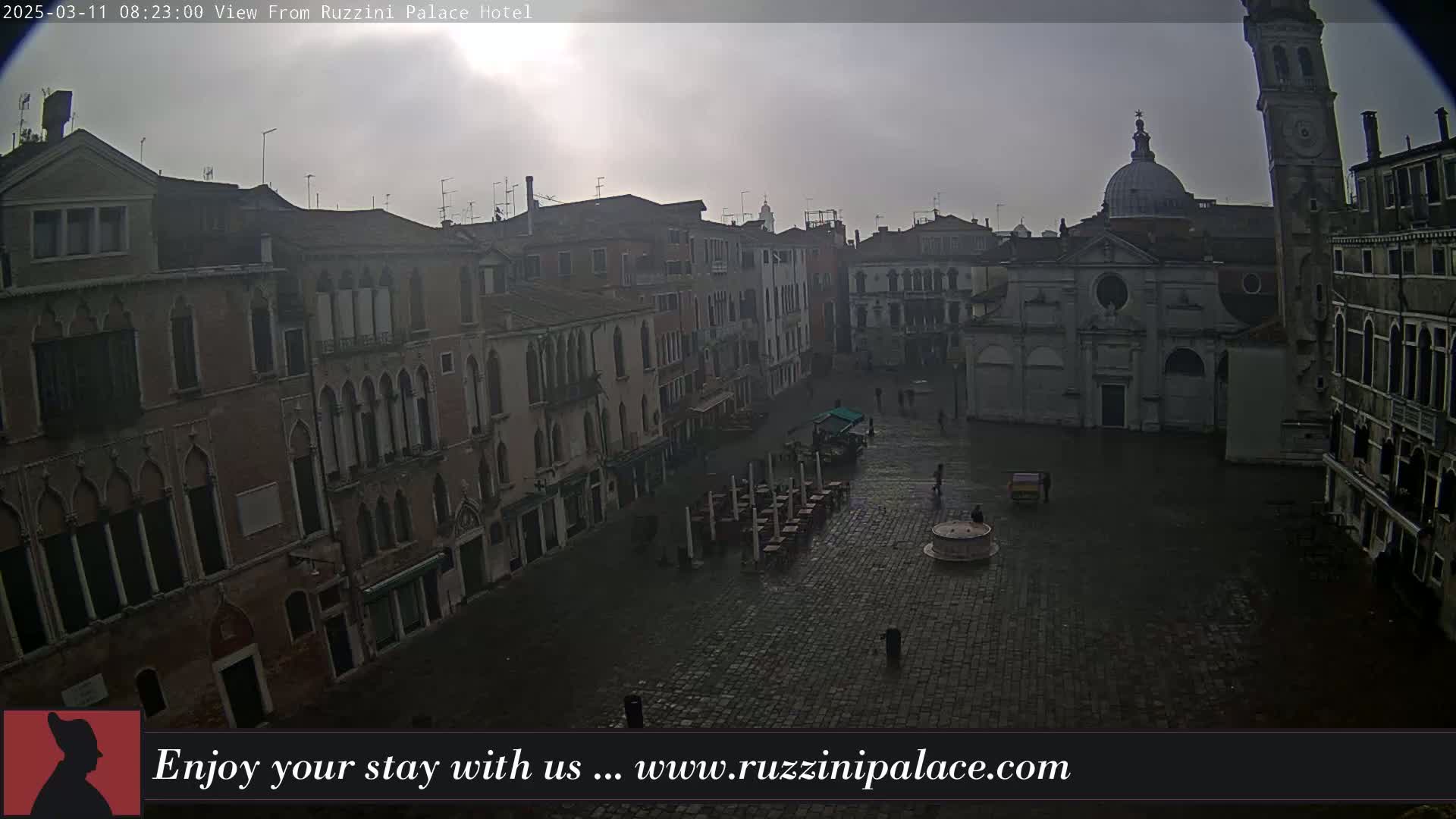 A mostly empty cobblestone square in Venice, Italy, is surrounded by old buildings under an overcast sky.