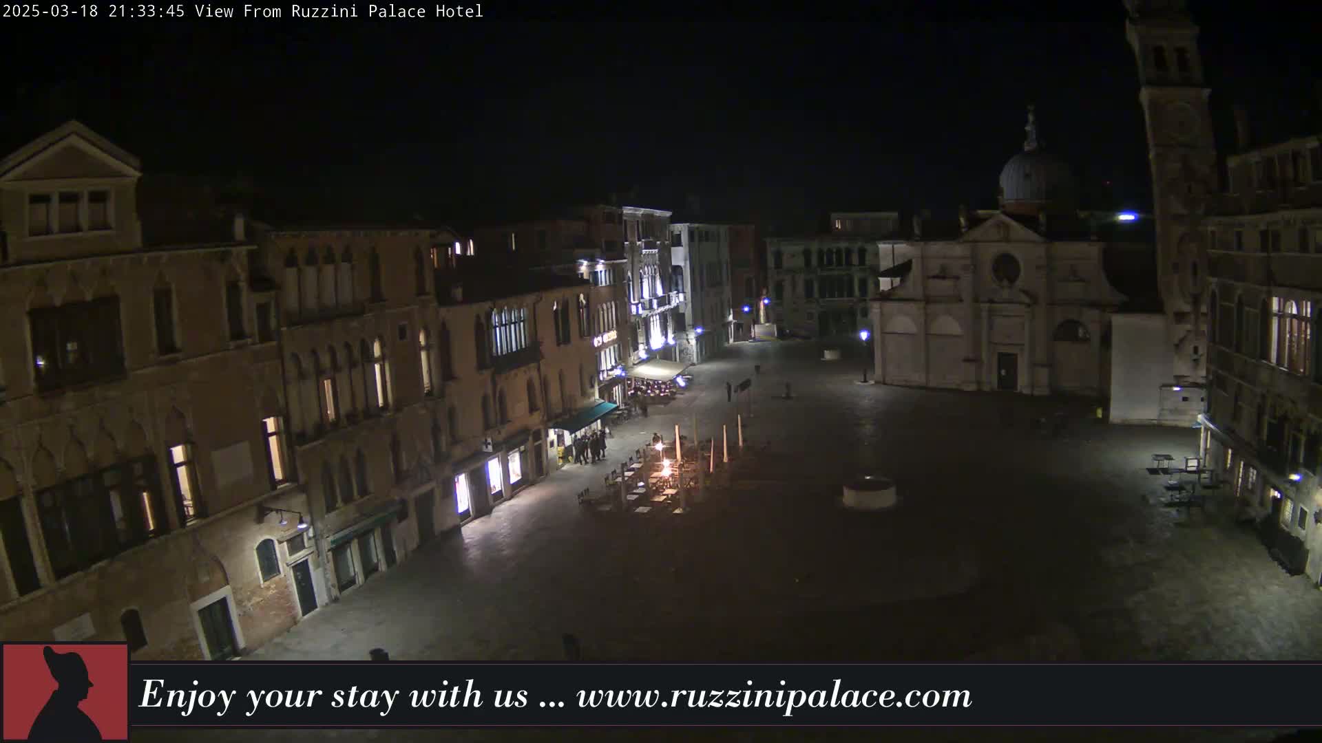 A nighttime, high-angle view of a dimly lit, cobblestone square in Venice, Italy, surrounded by historic buildings.