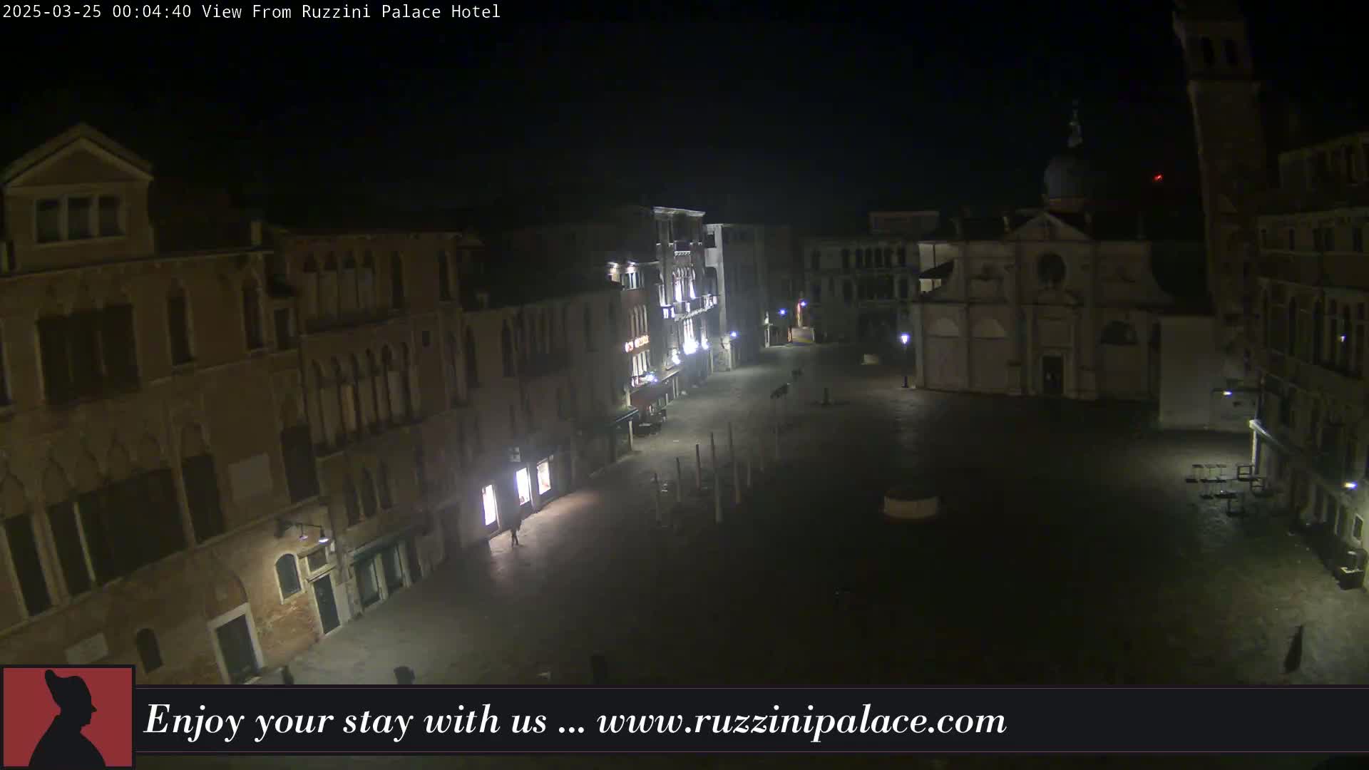 A nighttime, dimly lit view of a square in Venice, Italy, surrounded by old buildings.