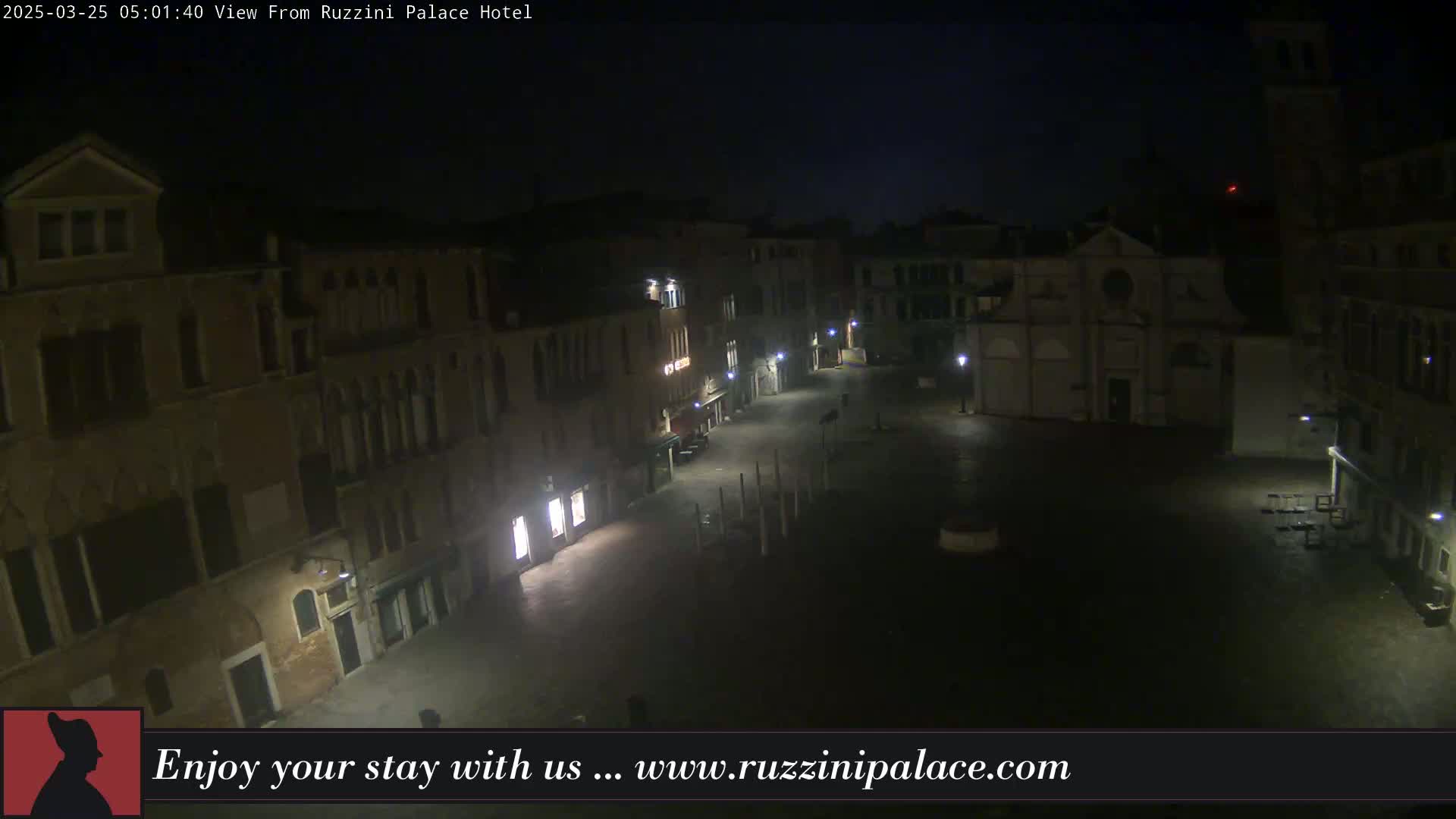 A dark, nighttime view of a quiet Venetian square, surrounded by old buildings.