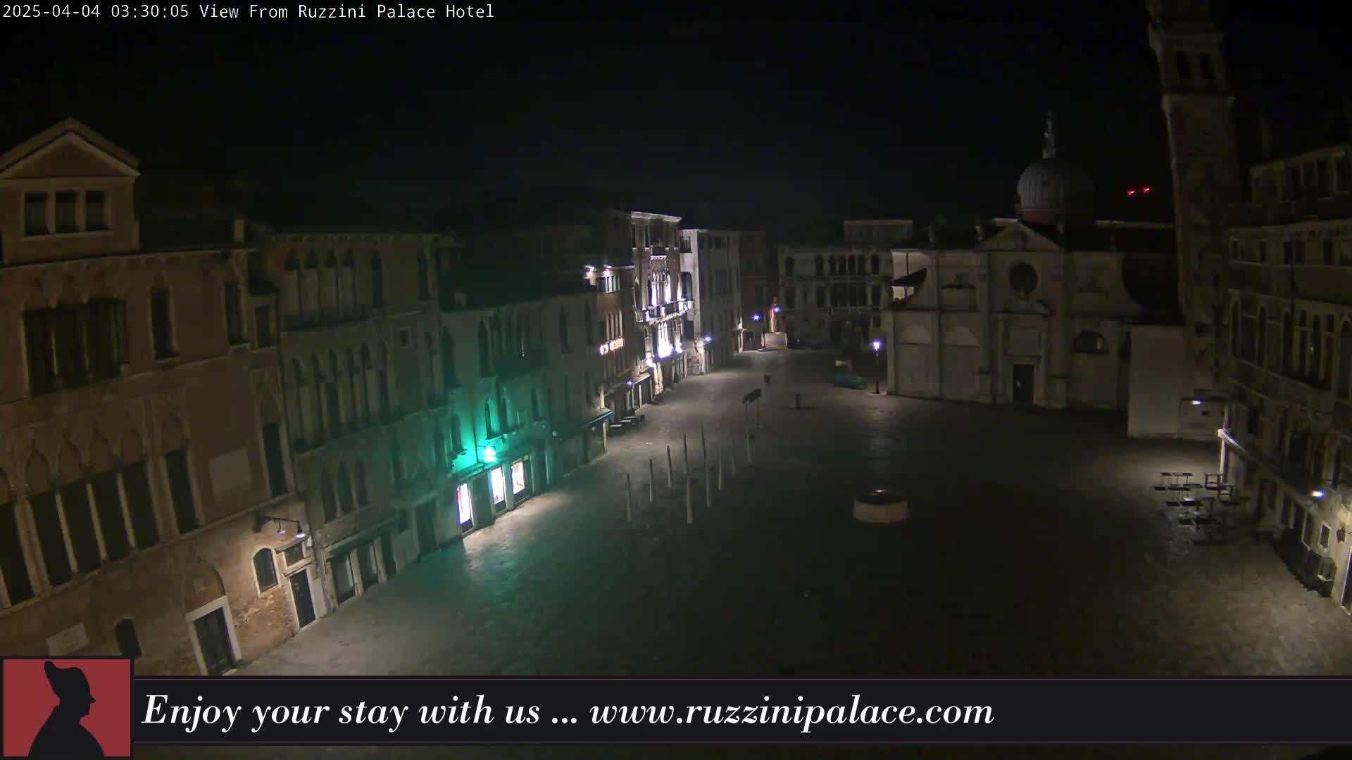 A nighttime view of a dimly lit, empty square in Venice, surrounded by old buildings.