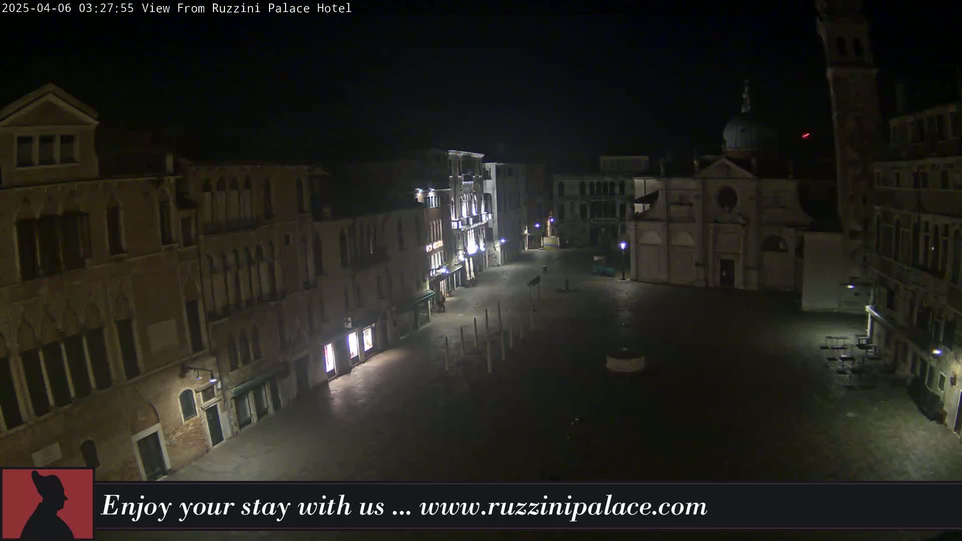 A nighttime view of a mostly empty cobblestone square in Venice, surrounded by illuminated buildings.