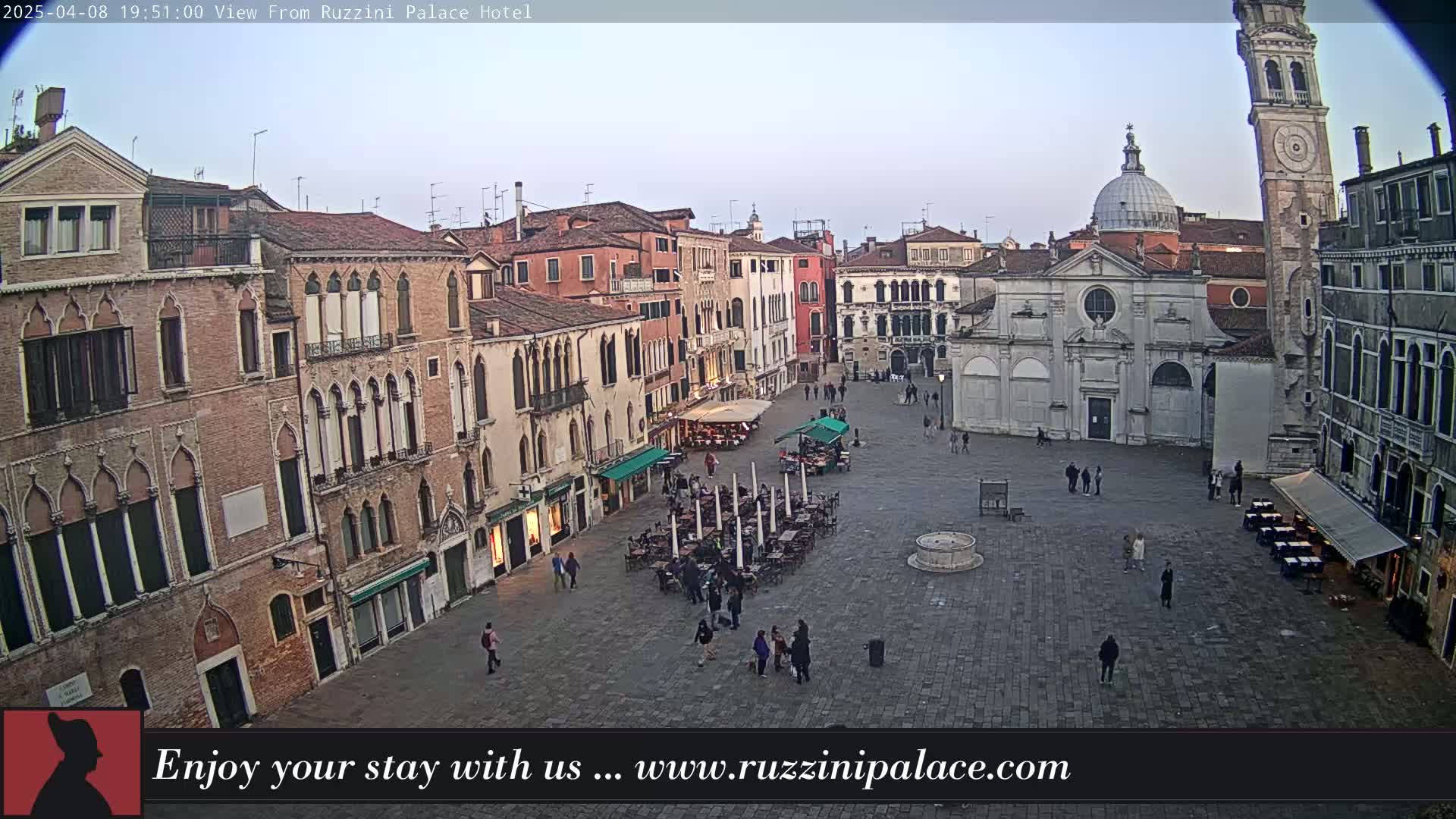 A mostly empty town square in Venice, Italy, is surrounded by old buildings under a pale, overcast sky.