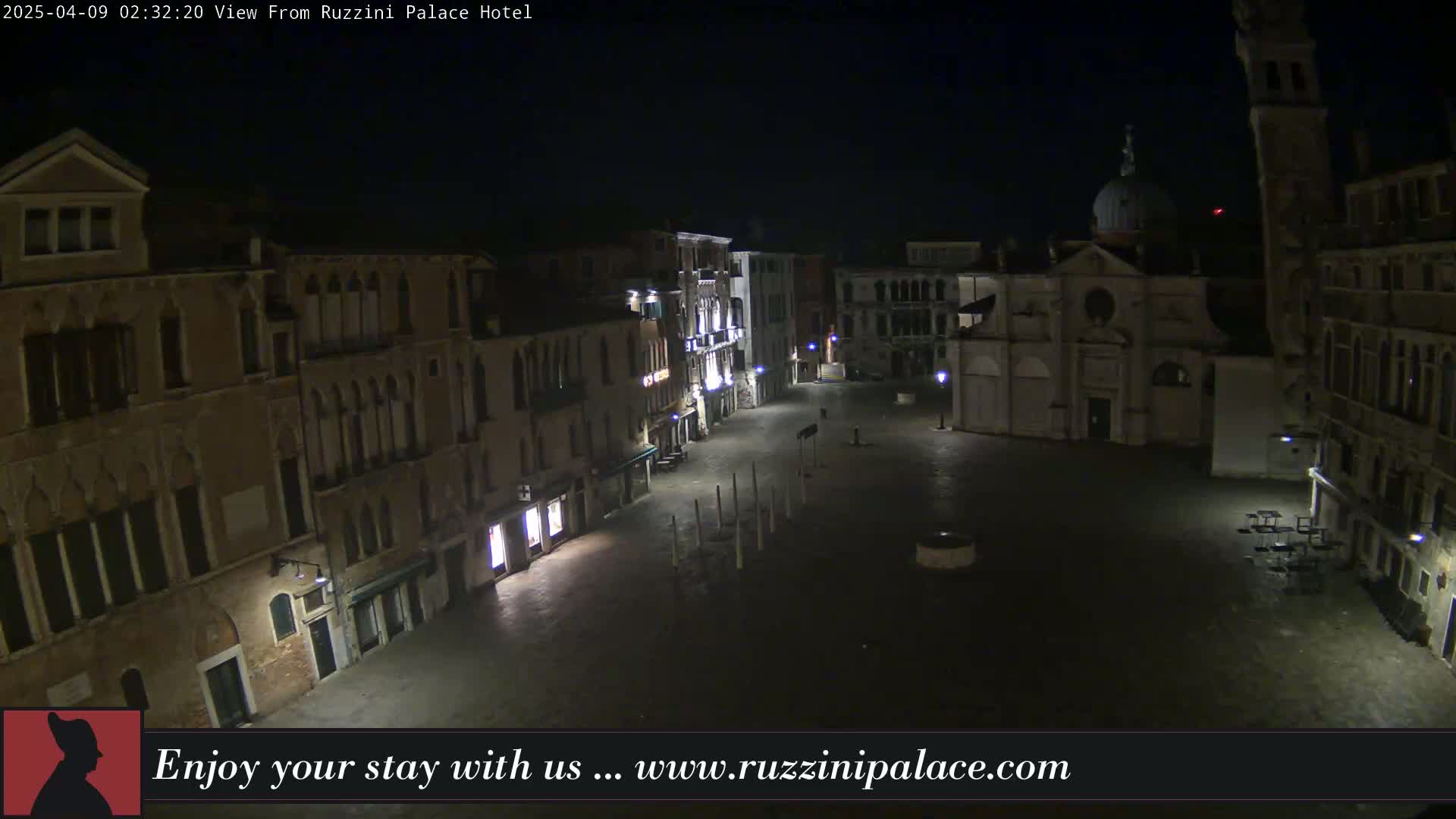 A nighttime, mostly empty, square in Venice, Italy, is surrounded by historic buildings under a dark sky.