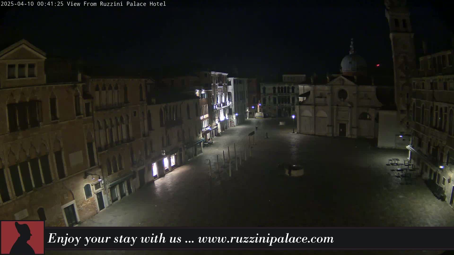 A nighttime, aerial view of a deserted, cobblestone square in Venice, surrounded by old buildings.