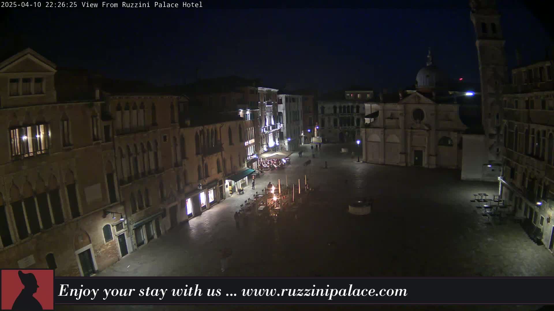 A nighttime aerial view shows a dimly lit, empty square in Venice, surrounded by old buildings.