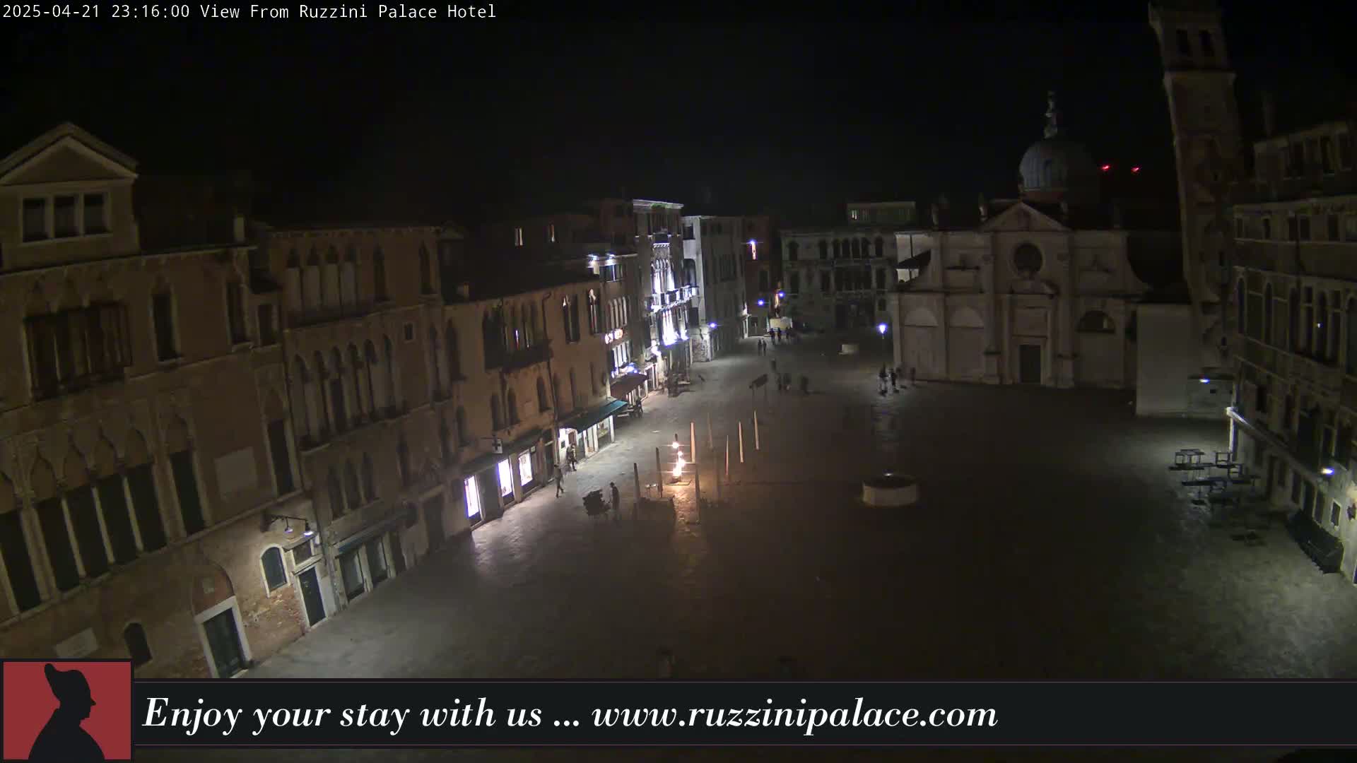 A nighttime view of a dimly lit, mostly empty square in Venice, surrounded by old buildings.