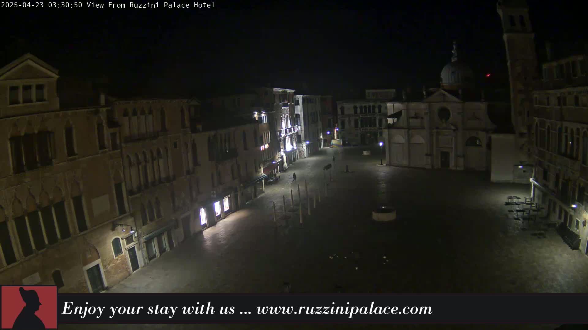 A dark, empty plaza at night is surrounded by old, multi-story buildings.