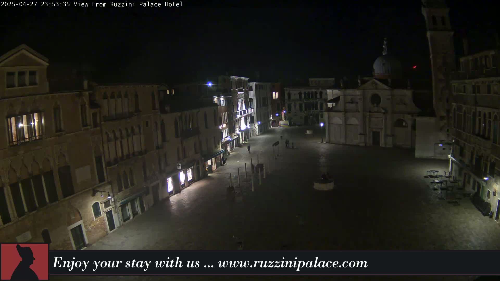 A nighttime view of a dimly lit, mostly empty square in Venice, surrounded by old buildings.