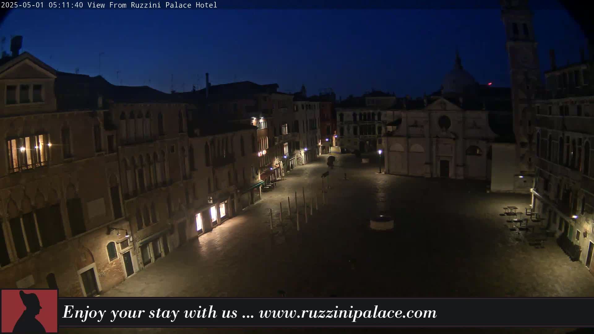 A mostly empty, dimly lit square in Venice at night, surrounded by ancient buildings under a dark blue sky.
