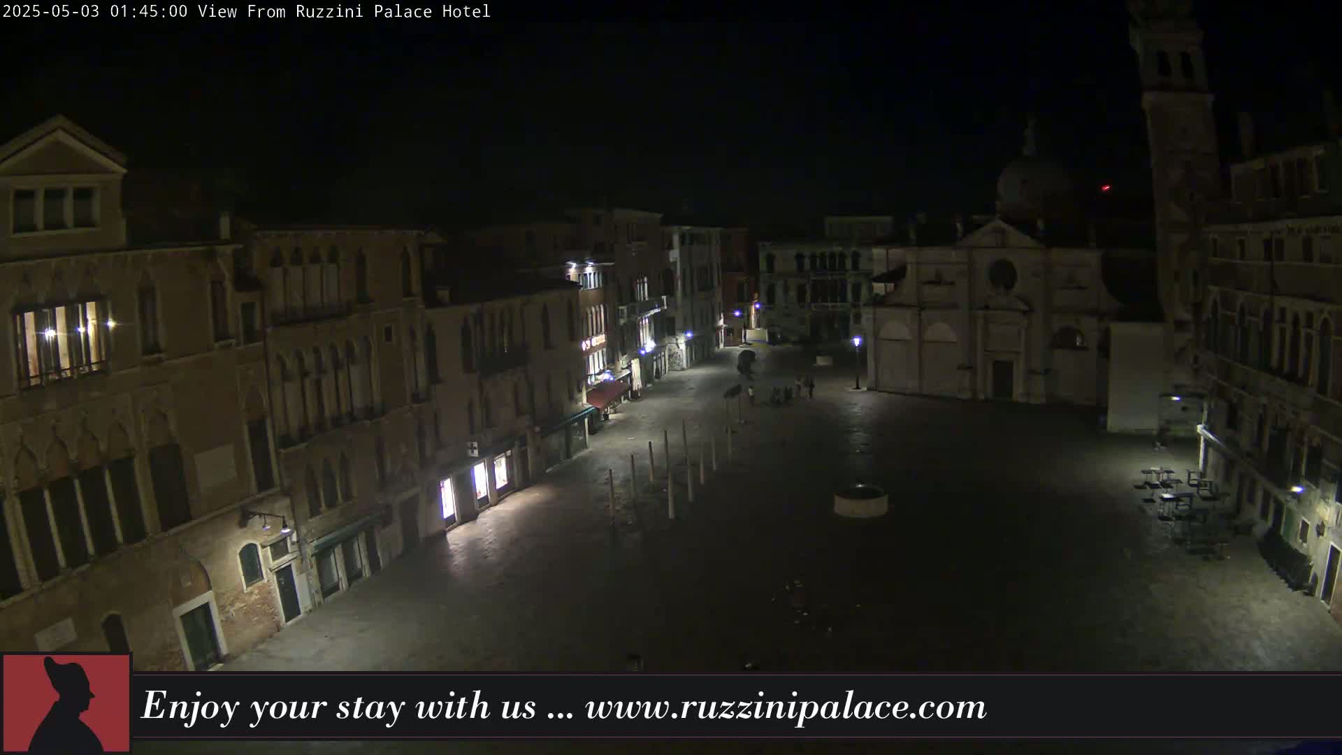A nighttime view of a dimly lit, mostly empty square in Venice, surrounded by old buildings.