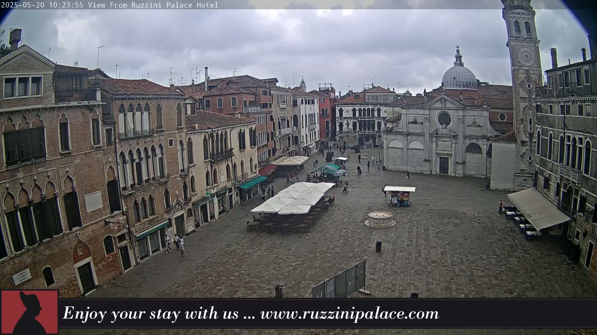 A mostly empty cobblestone square in Venice, Italy, is surrounded by old brick buildings under an overcast sky.