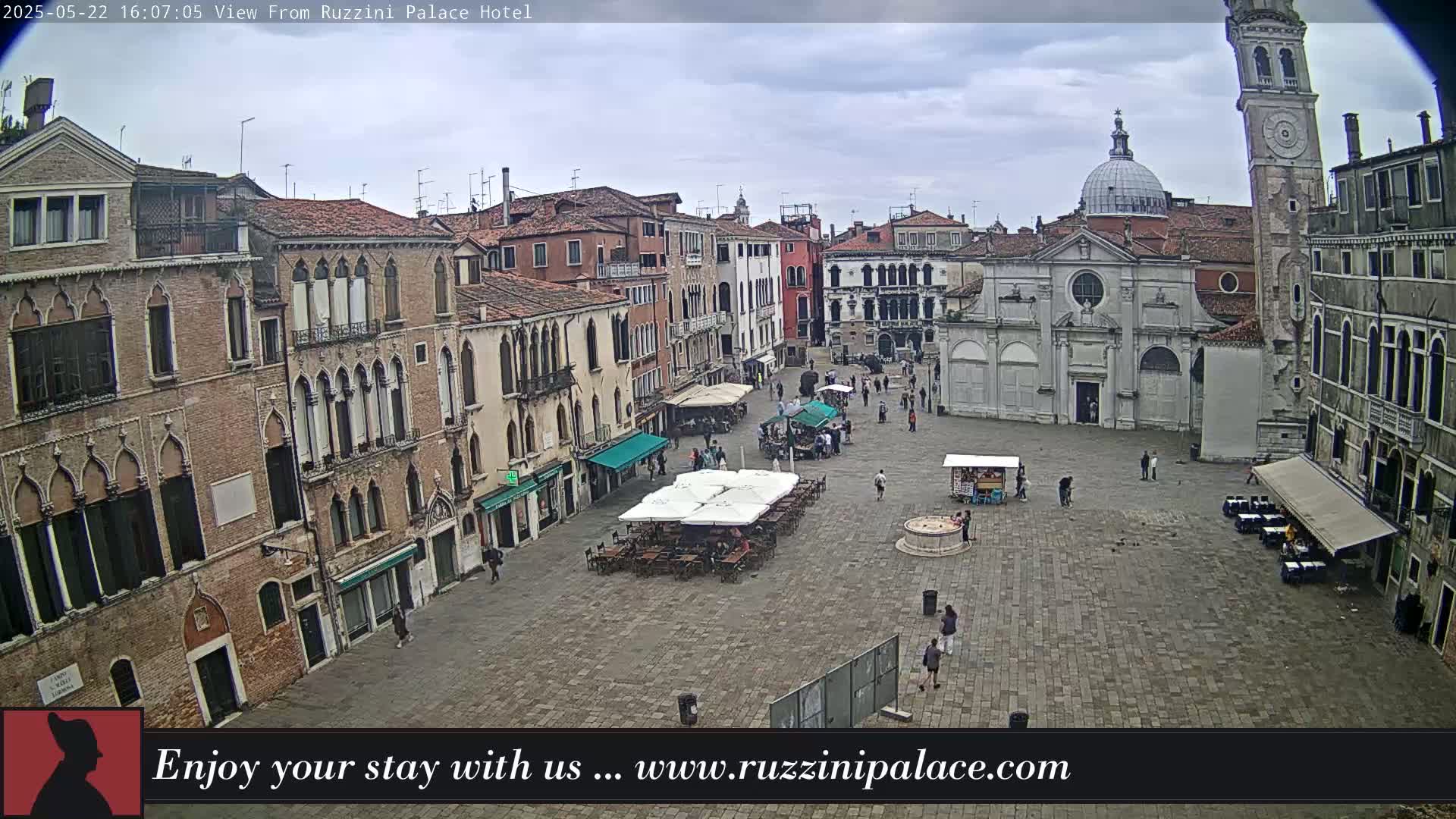 A mostly empty, stone plaza in Venice, Italy, is surrounded by several-story buildings under an overcast sky.