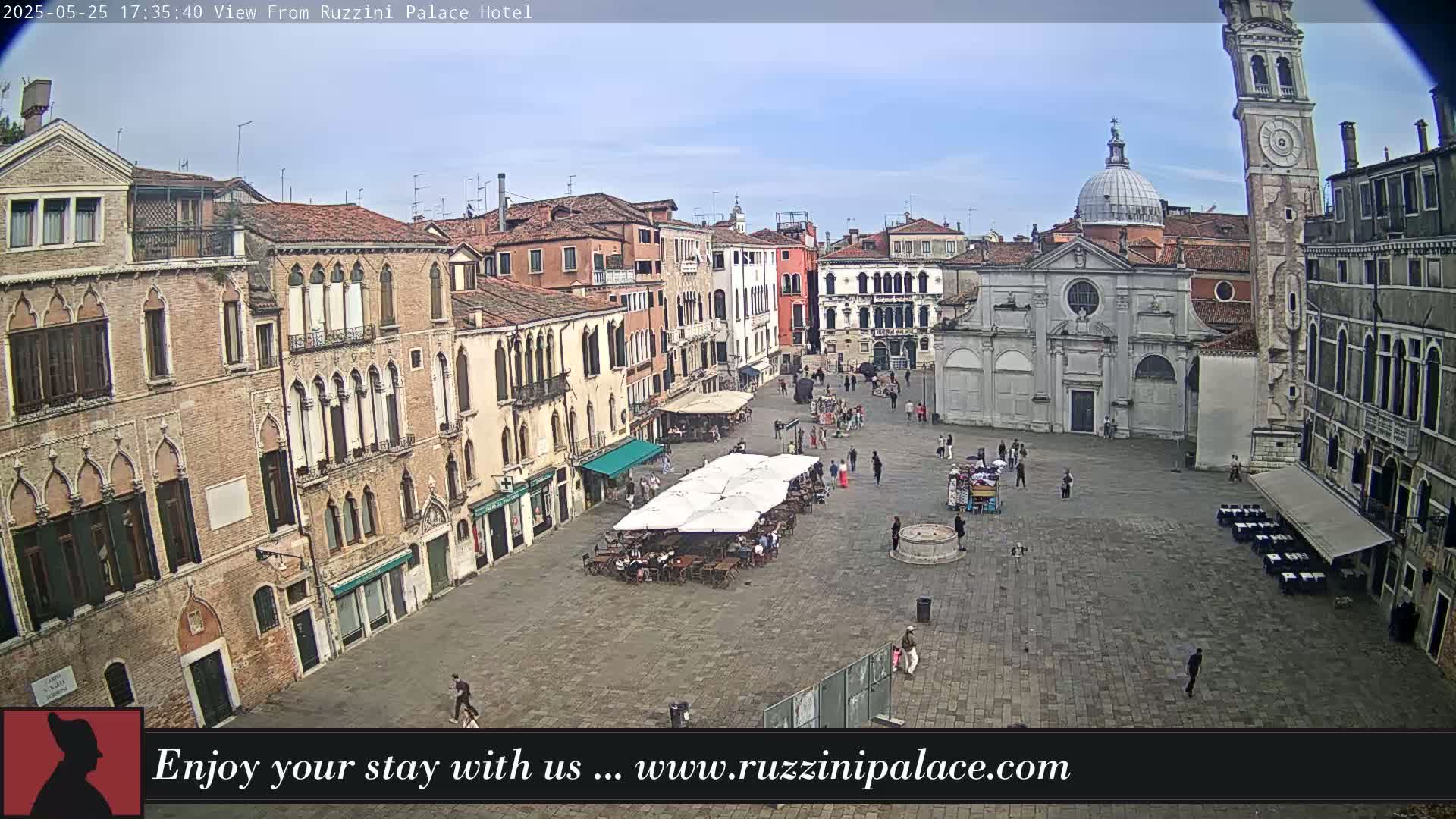 A mostly empty cobblestone square in Venice, Italy, is surrounded by old buildings under a partly cloudy sky.