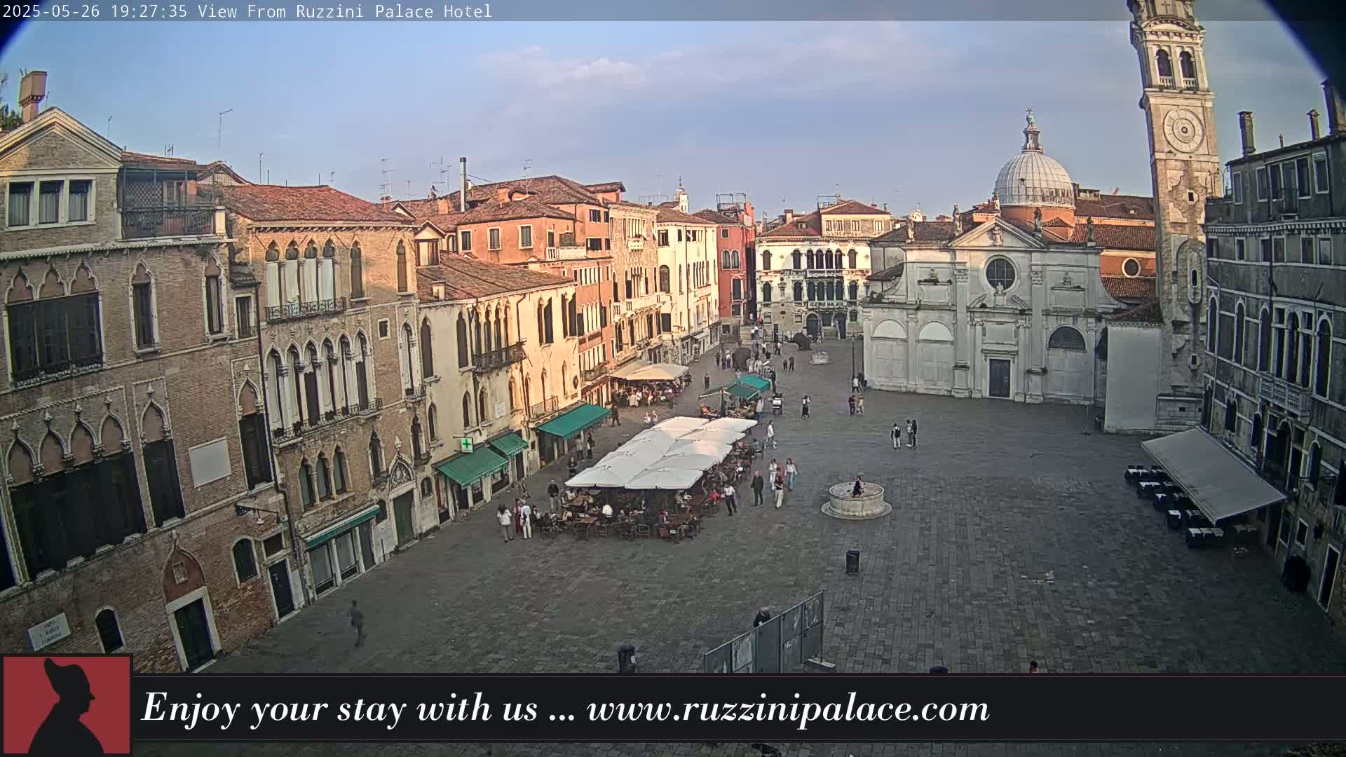 A mostly empty cobblestone square in Venice, Italy, is surrounded by historic buildings under a clear, twilight sky.