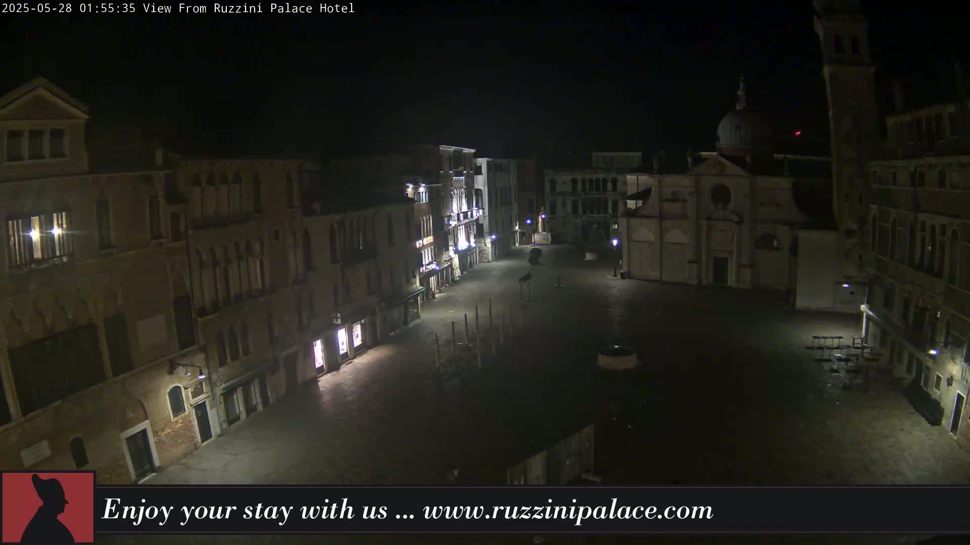A nighttime, aerial view of a deserted, cobblestone square in Venice, surrounded by old buildings.
