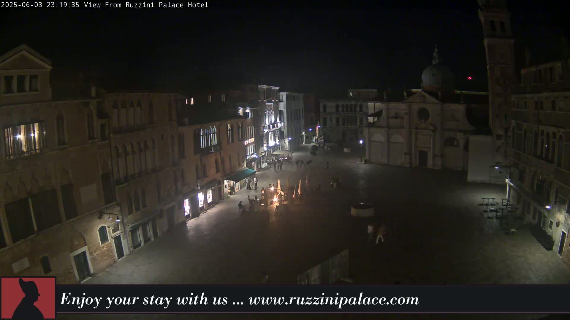 A nighttime aerial view of a dimly lit European plaza surrounded by old buildings.