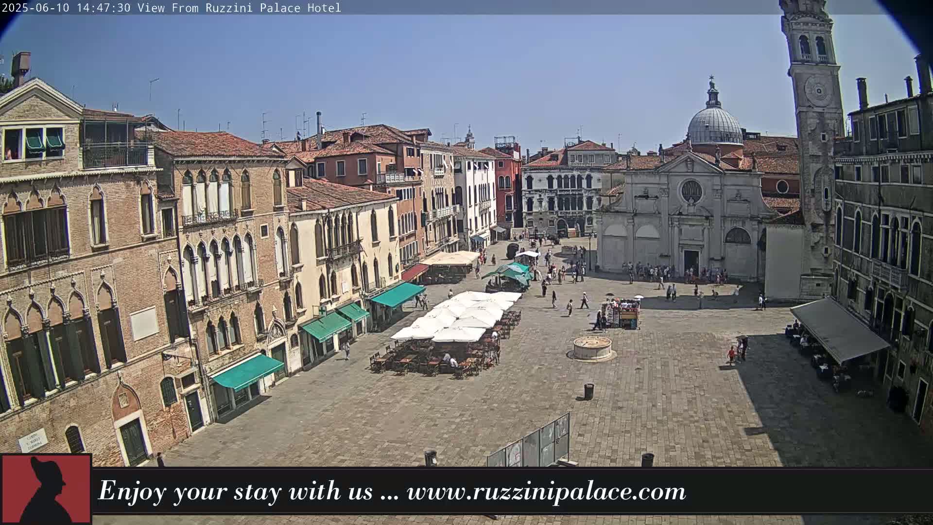 A sunny Venetian square, surrounded by historic buildings, features outdoor seating under umbrellas and a few people strolling about.