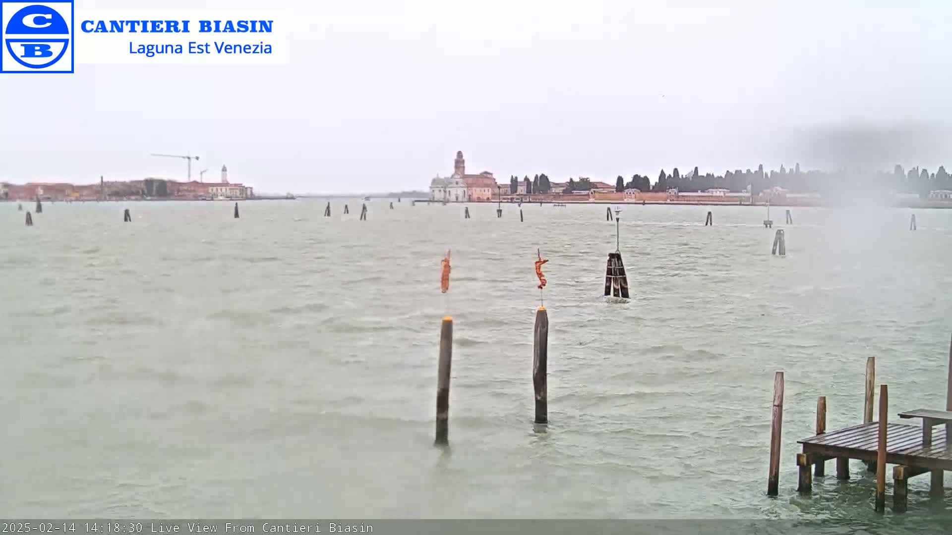 A view across a choppy body of water shows a distant island with buildings under an overcast sky.