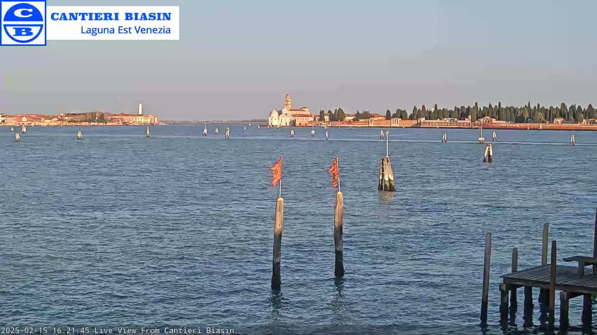 A calm body of water shows a distant island with buildings under a clear sky.