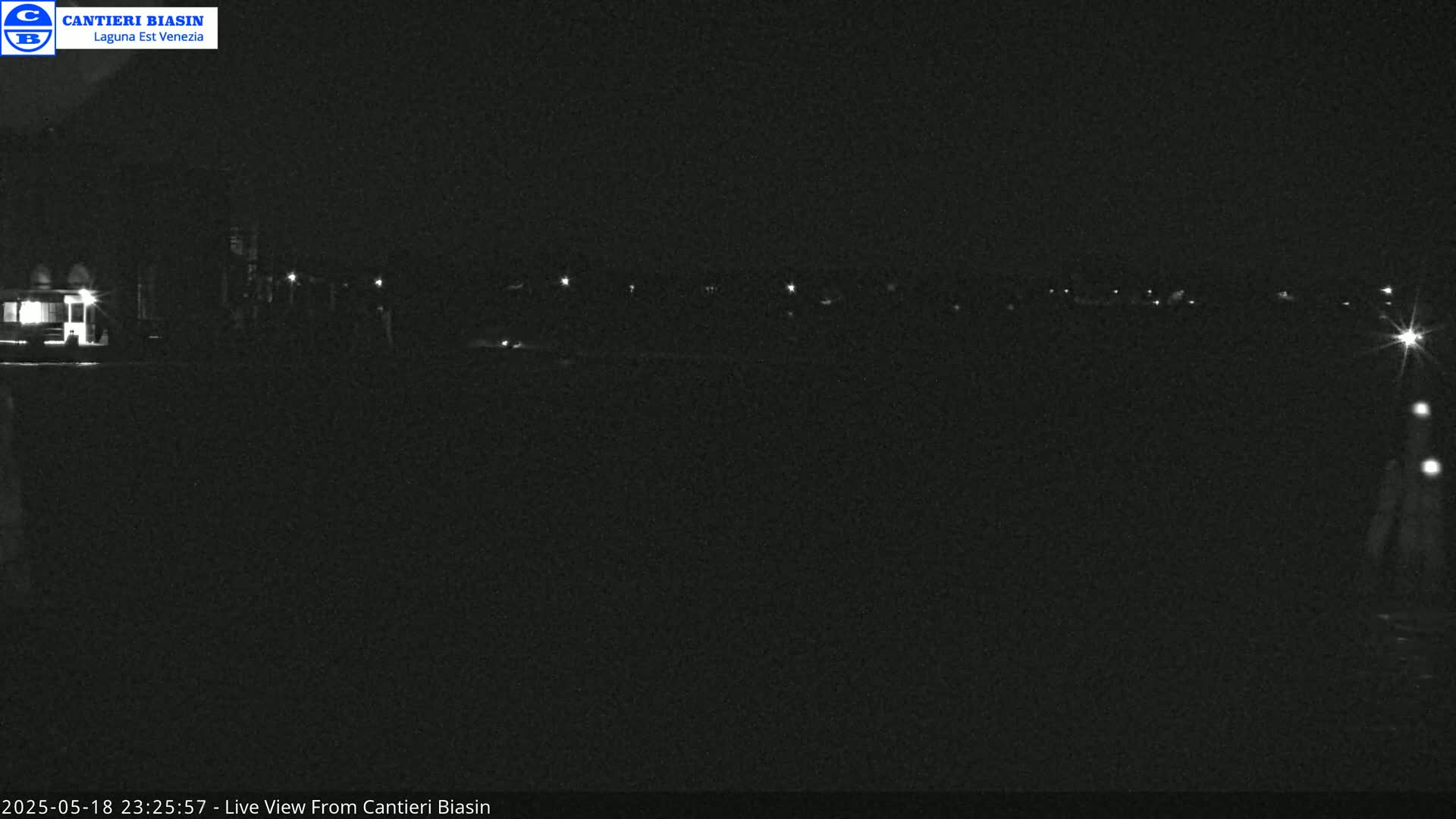A nighttime, low-light view of a dark, flat landscape with a few distant lights.