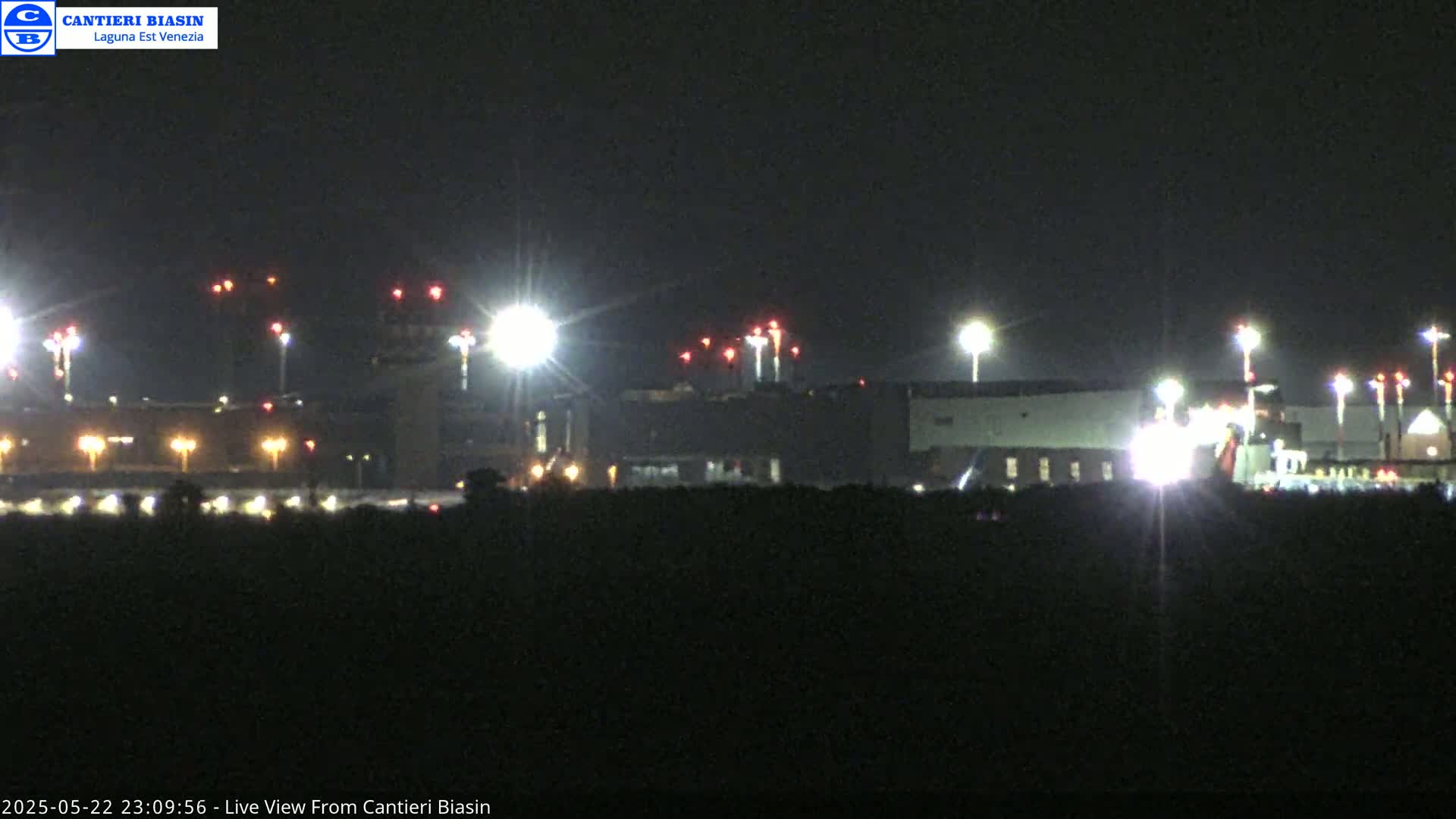 At night, brightly lit airport buildings and runways are visible from a distance.