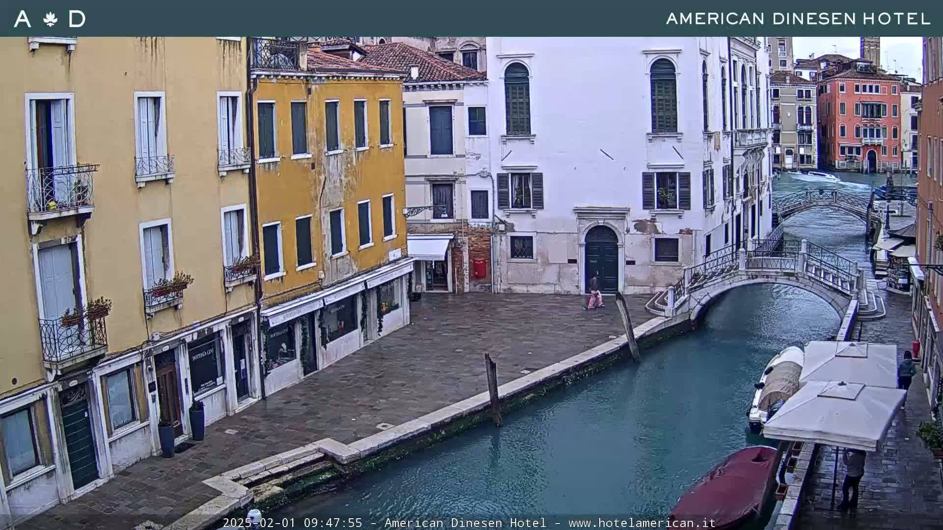 A canal in Venice, Italy, shows overcast weather with buildings lining the waterway and a small bridge crossing it.