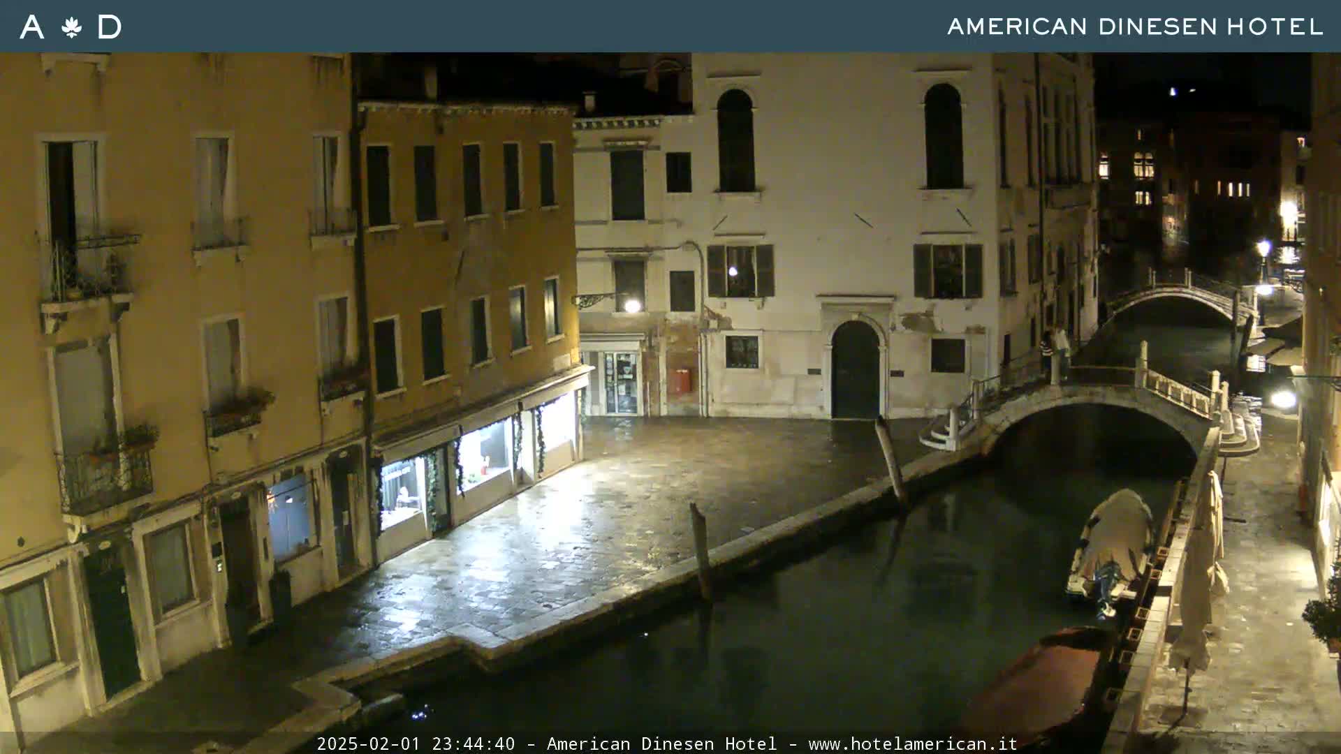 A nighttime view of a canal in Venice, with buildings lining the waterway and a small boat moored nearby.