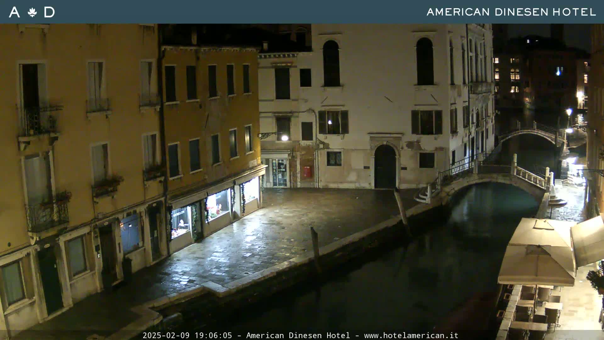 A nighttime view of a canal in Venice, with buildings lining the waterway and a small bridge spanning the canal.