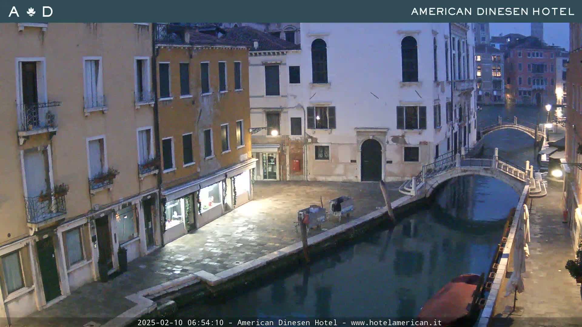 A canal in Venice at twilight, with stone buildings lining its banks and a small bridge spanning the water.