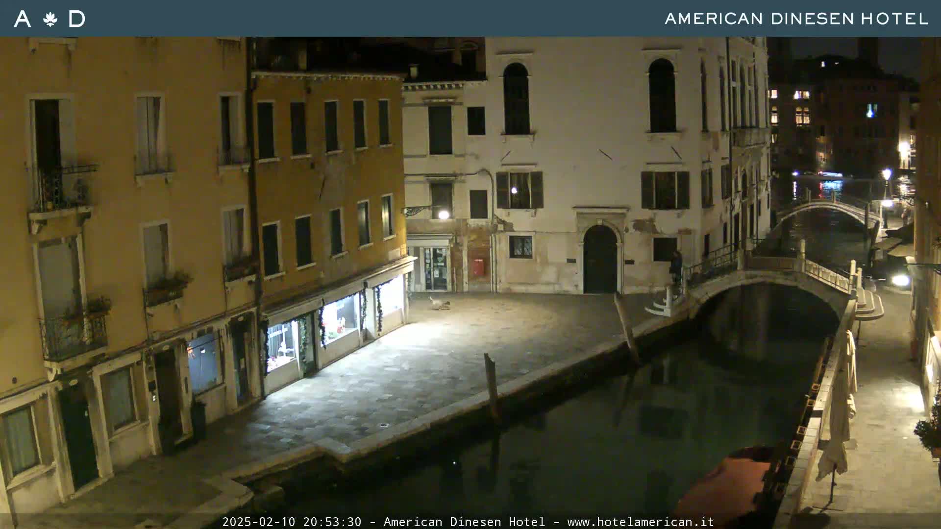 A nighttime view of a canal in Venice, showing several buildings along the waterway and a bridge spanning the canal.