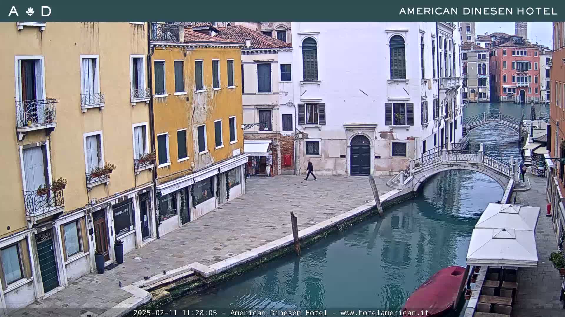 A canal in Venice, Italy, on an overcast day, is flanked by buildings and a pedestrian bridge.