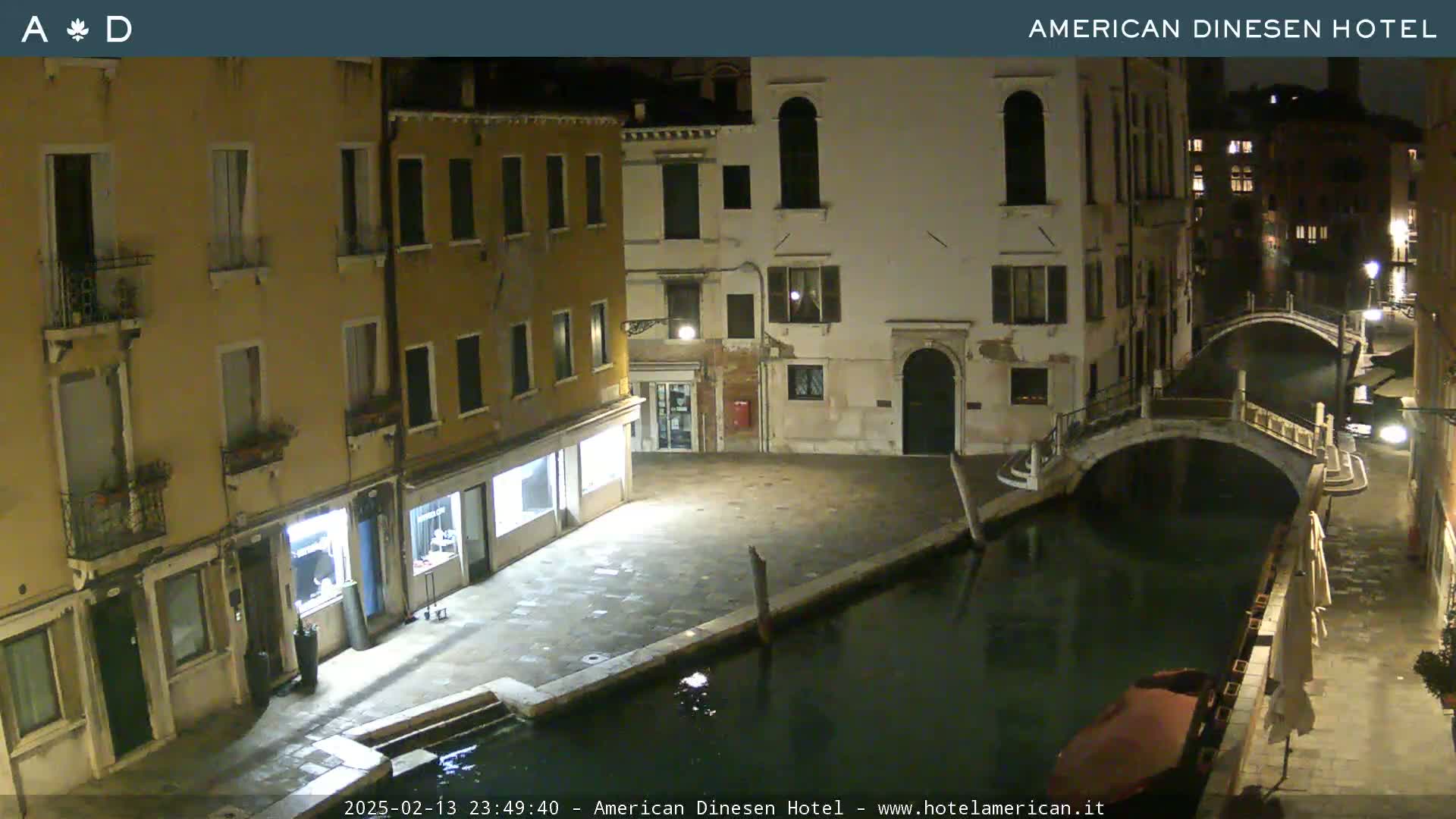 A nighttime view of a canal in Venice, showing buildings lining the waterway and a small bridge.