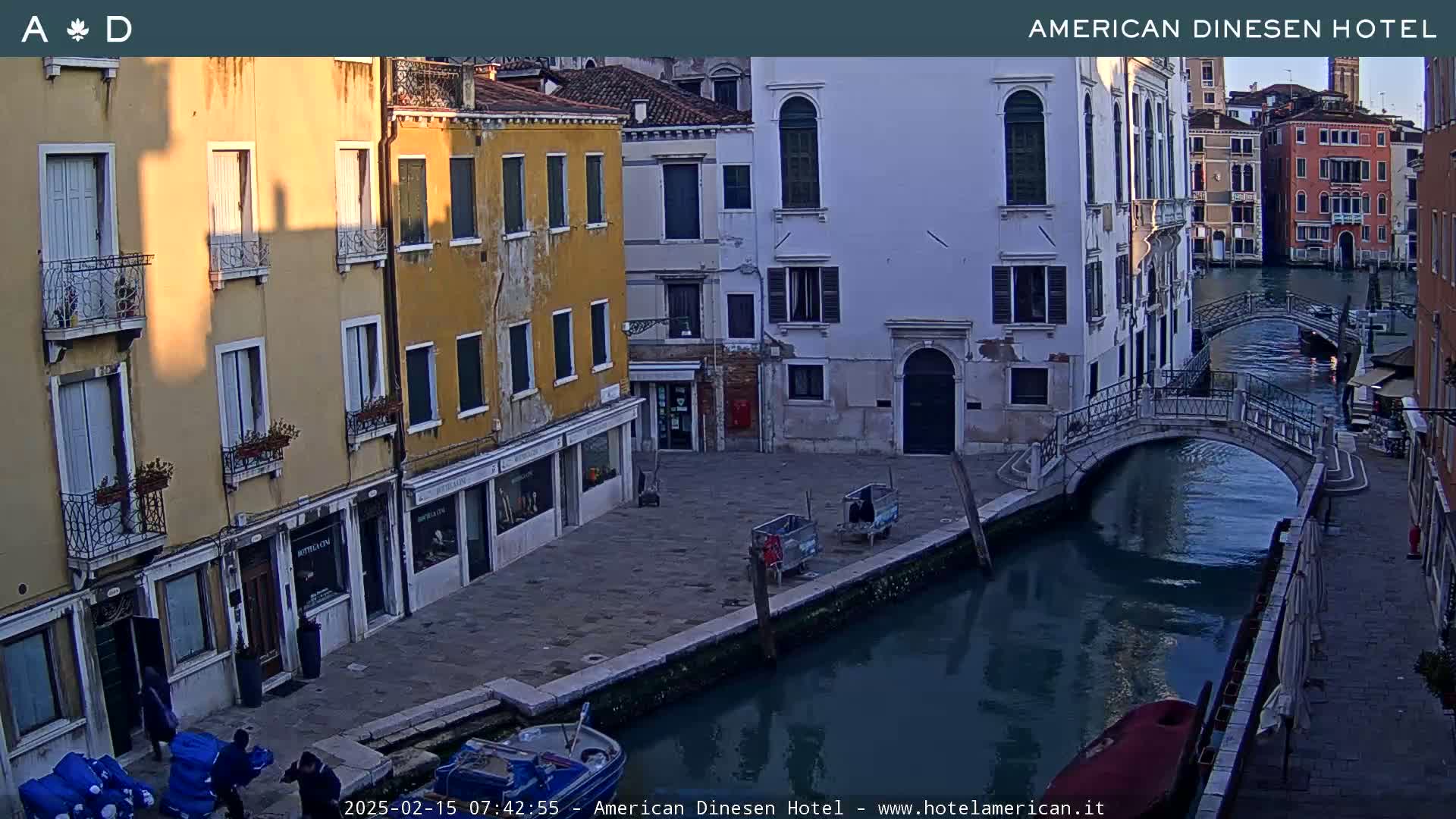 A calm canal in Venice, lined with old buildings, is bathed in the soft light of sunrise or sunset.