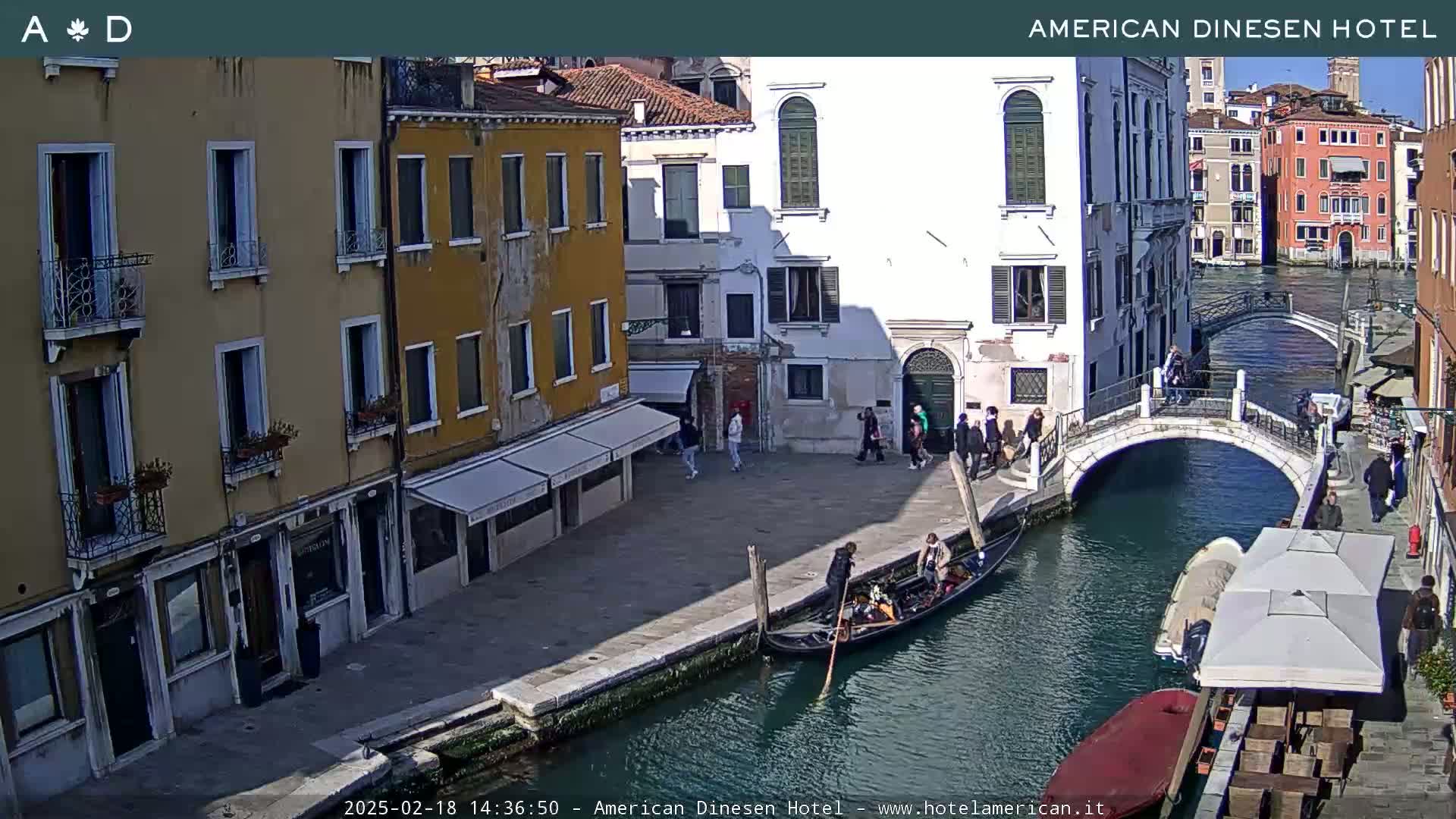 A gondola floats in a canal beside buildings in Venice under a sunny sky.