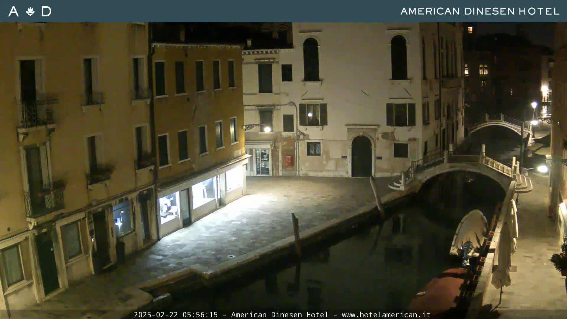 A nighttime view of a canal in Venice, Italy, with buildings lining the waterway and a small bridge crossing the canal.