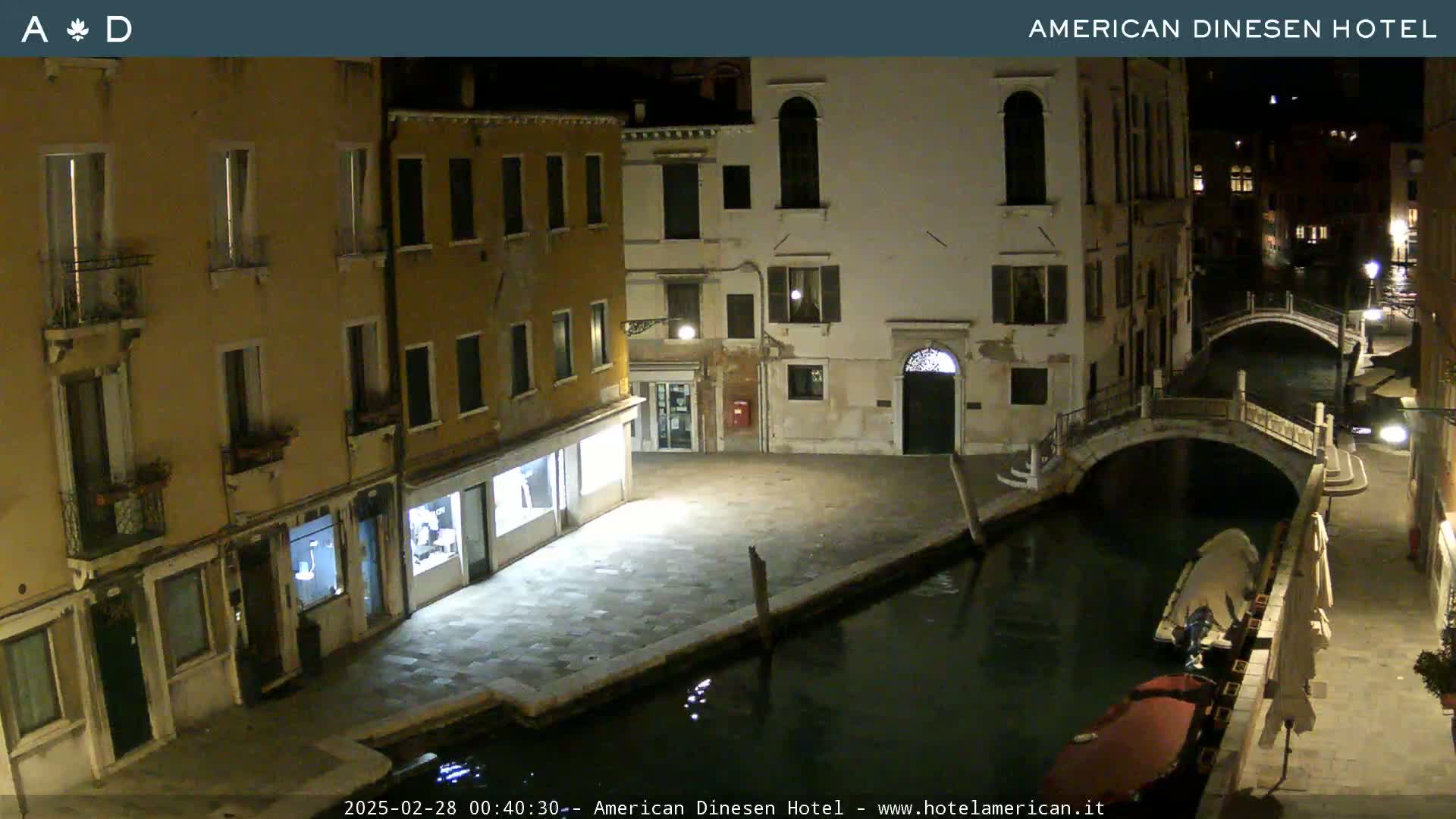 A nighttime view of a canal in Venice, Italy, with buildings lining the waterway and a gondola moored nearby.