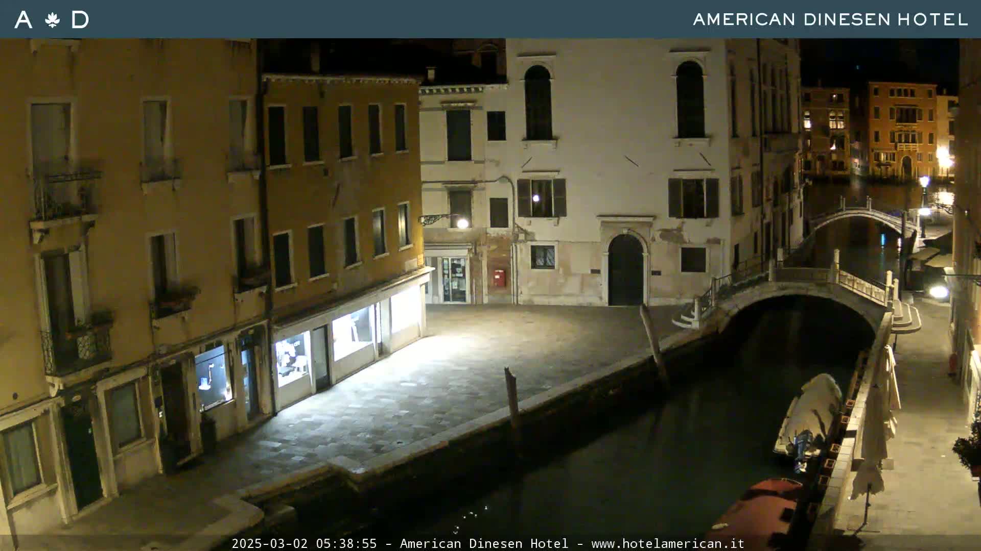 A nighttime view of a canal in Venice, showing buildings lining the waterway and a small bridge spanning the canal.