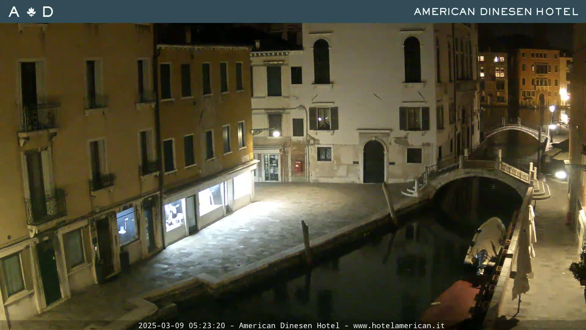 A nighttime view of a canal in Venice, showing several buildings and a small bridge.