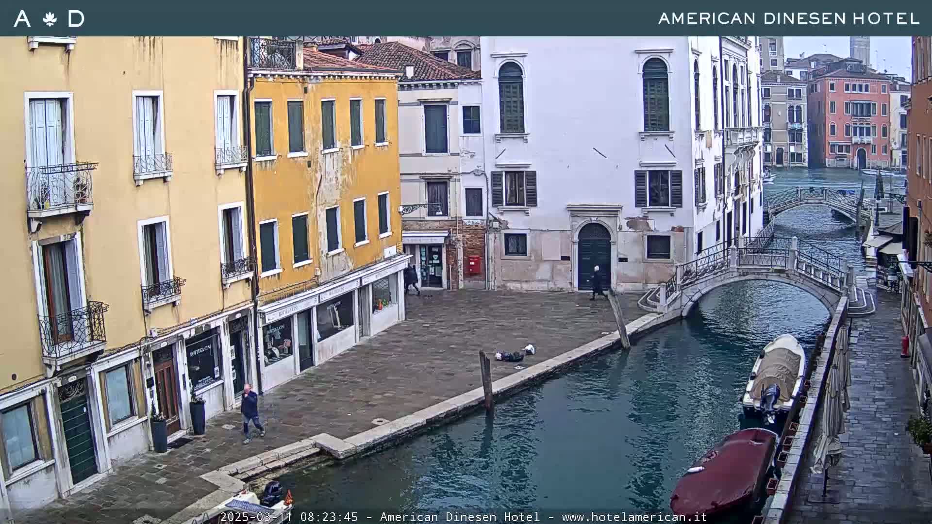 A canal in Venice, Italy, with several buildings lining the waterway and a bridge crossing the canal, under an overcast sky.