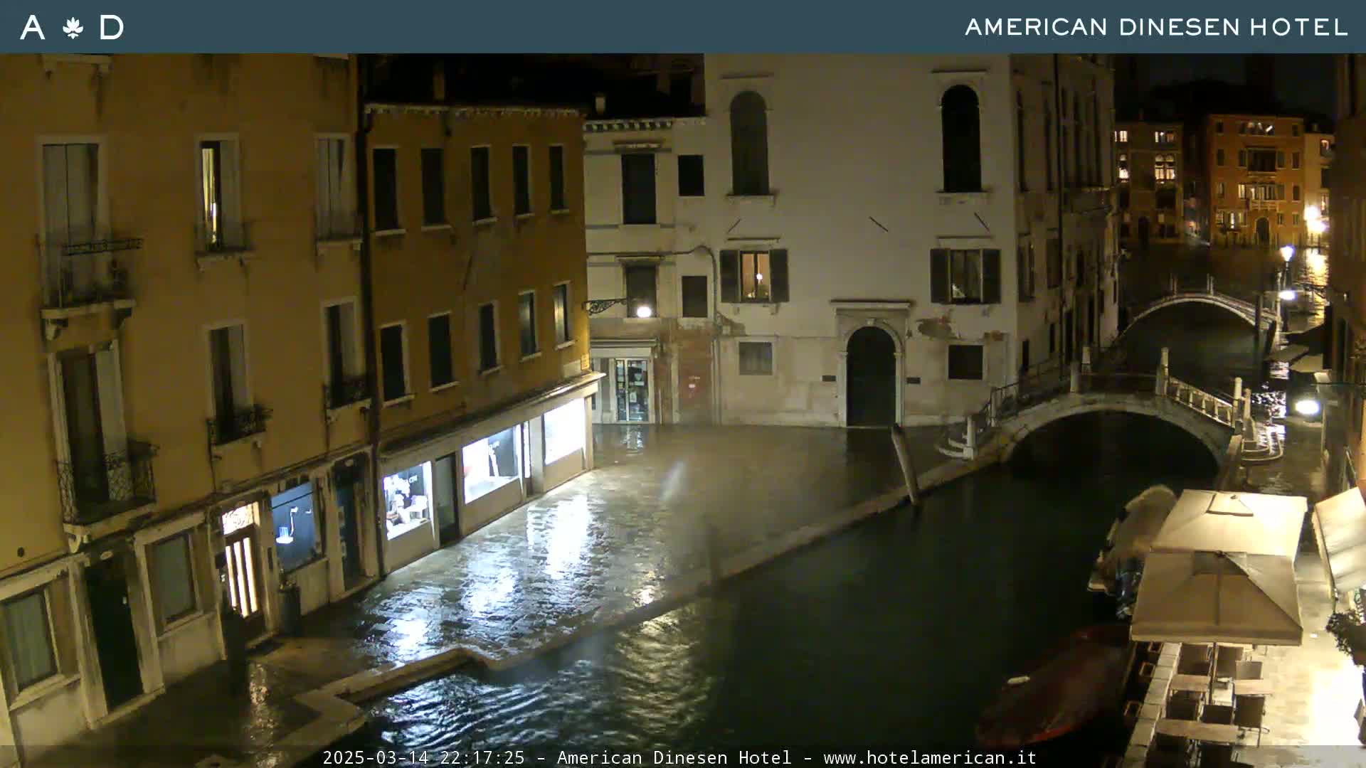 A nighttime view of a flooded Venetian canal and adjacent buildings under overcast skies.
