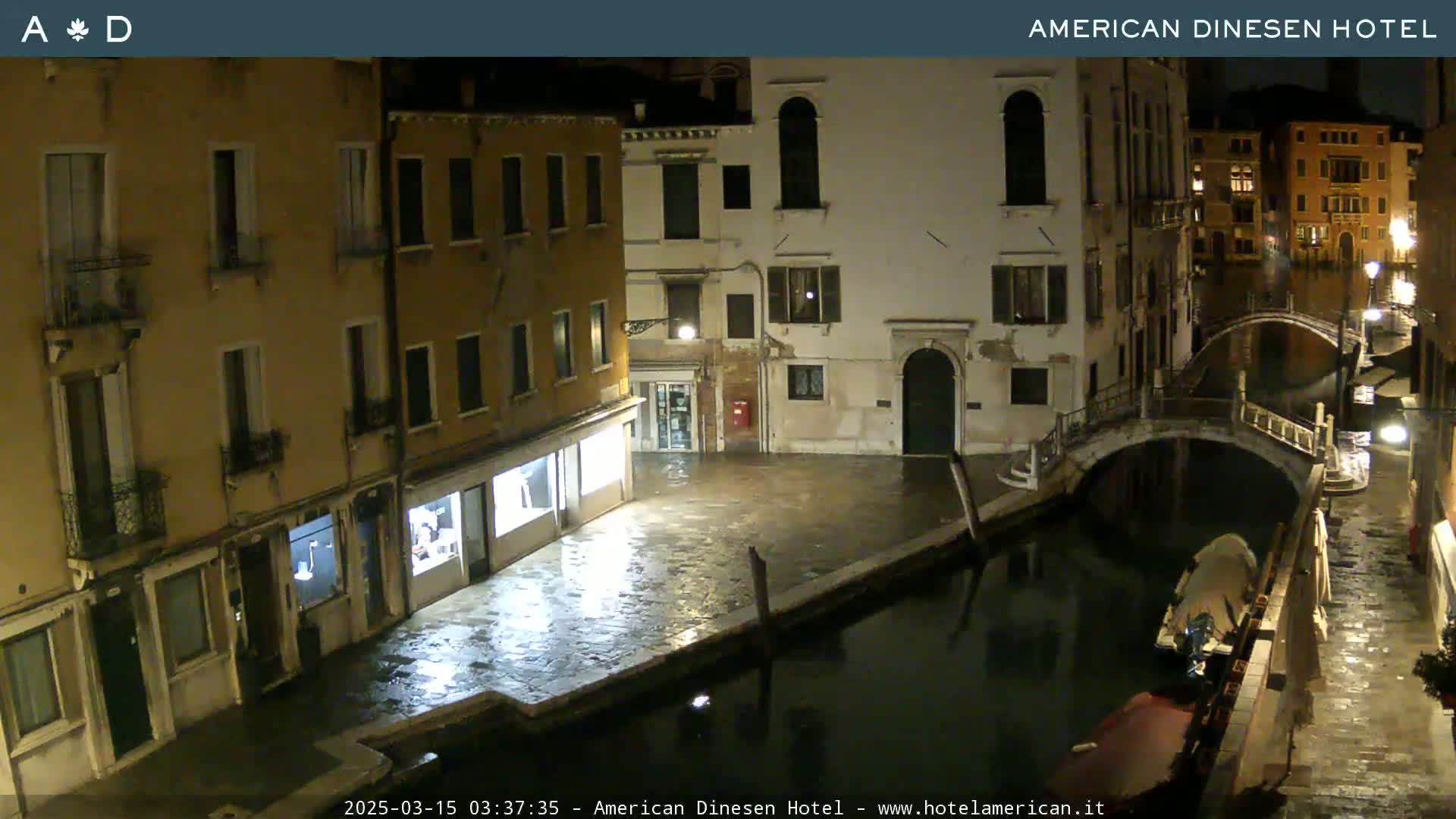 A nighttime view of a canal in Venice, with buildings lining the waterway and a bridge spanning the canal.