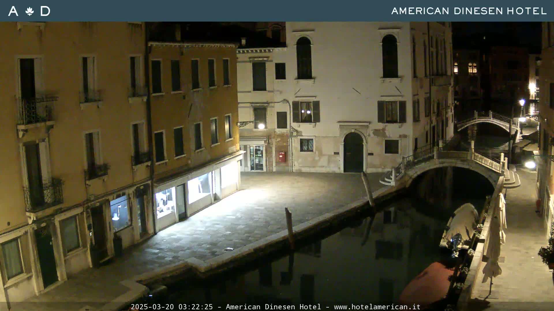 A nighttime view of a canal in Venice, Italy, with several buildings lining the waterway and a small bridge crossing the canal.