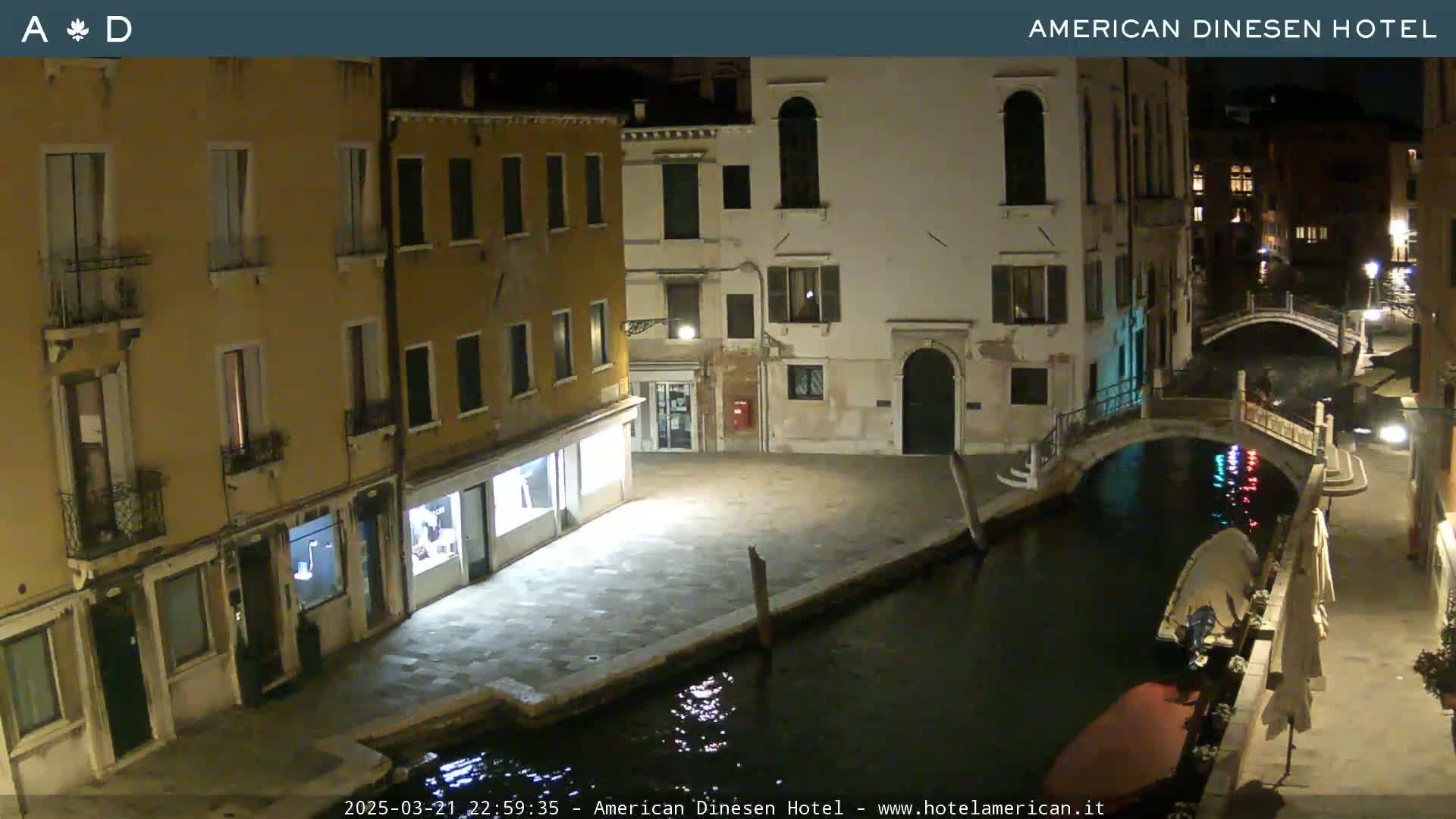A nighttime view of a canal in Venice, with several buildings lining the waterway and a small boat moored nearby.
