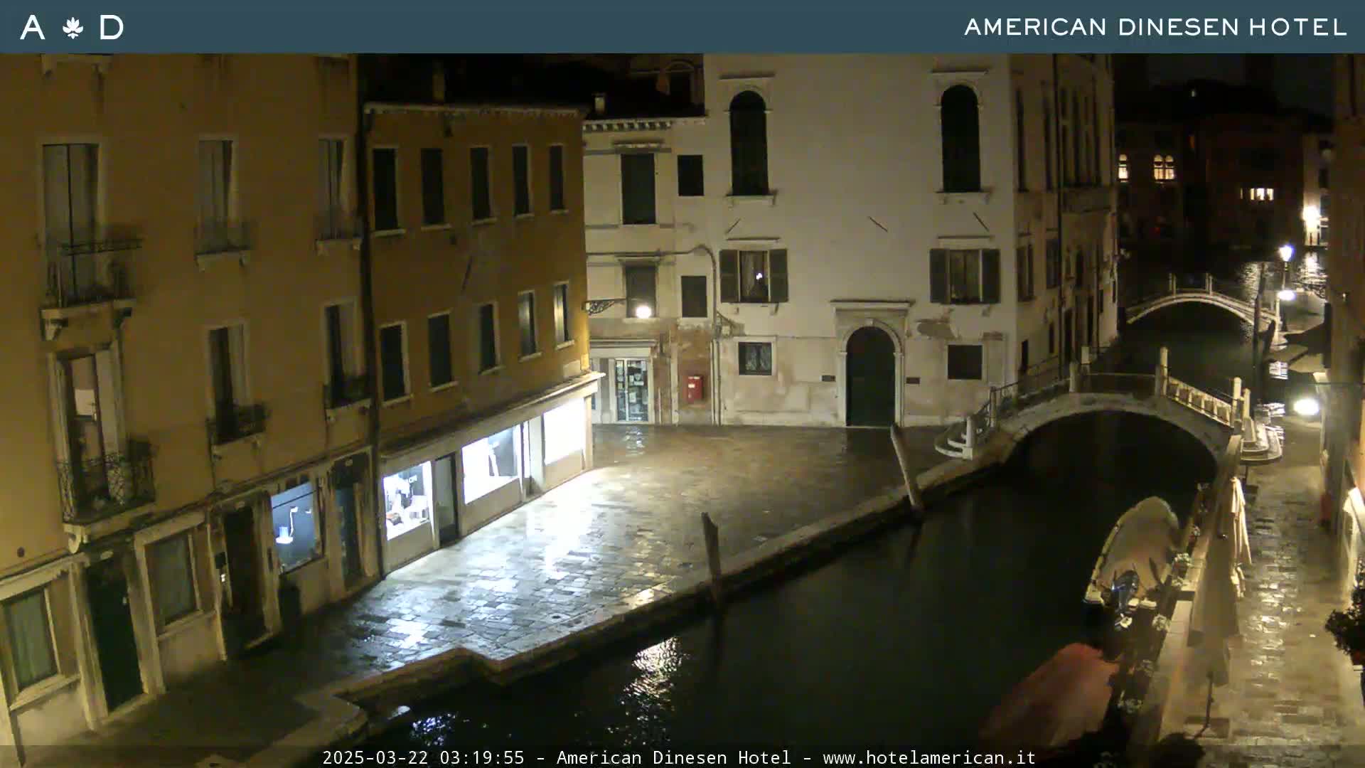 A nighttime view of a canal in Venice, showing buildings lining the waterway and a small bridge.