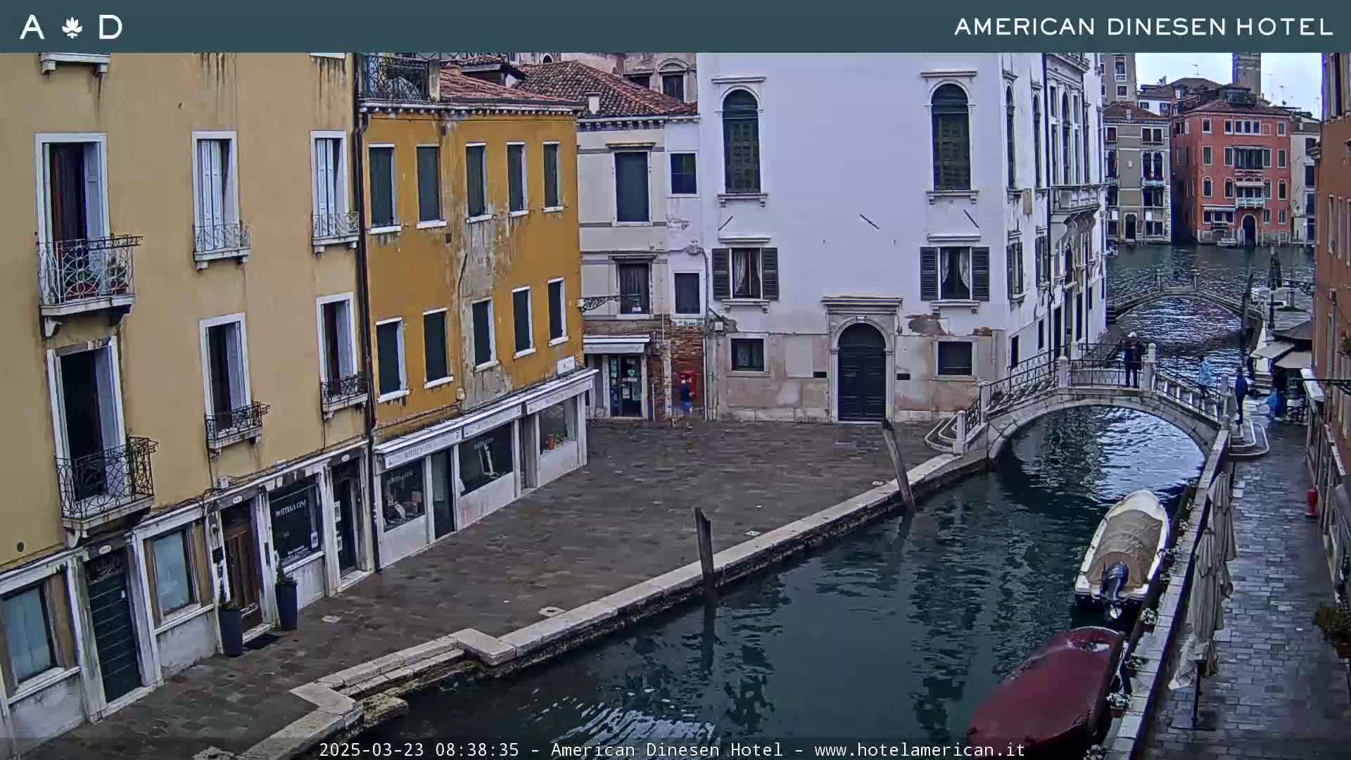 A canal in Venice, Italy, with several buildings lining the waterway and a small bridge, on an overcast day.