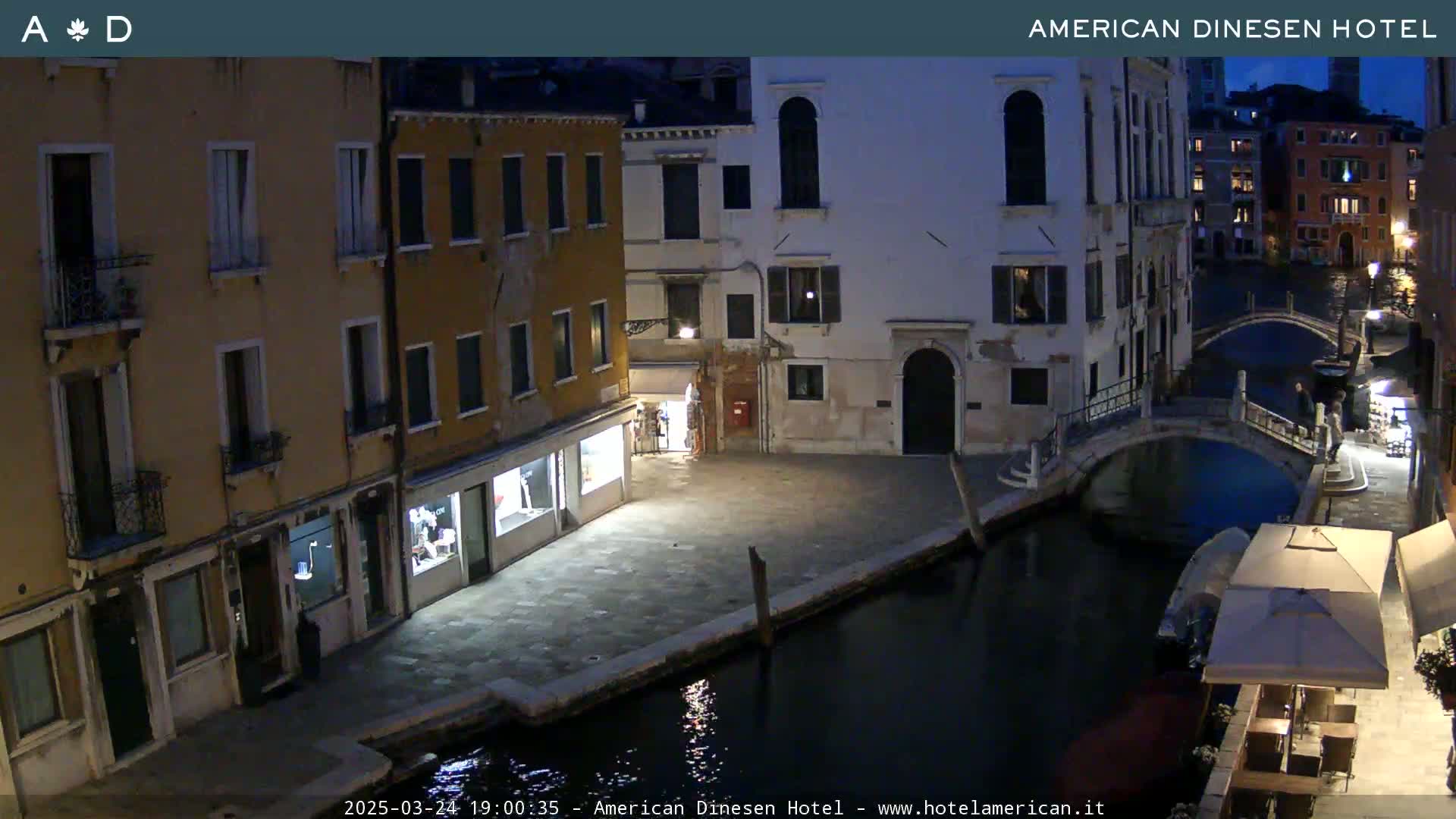 A nighttime view of a canal in Venice, showing buildings lining the waterway and a small bridge.