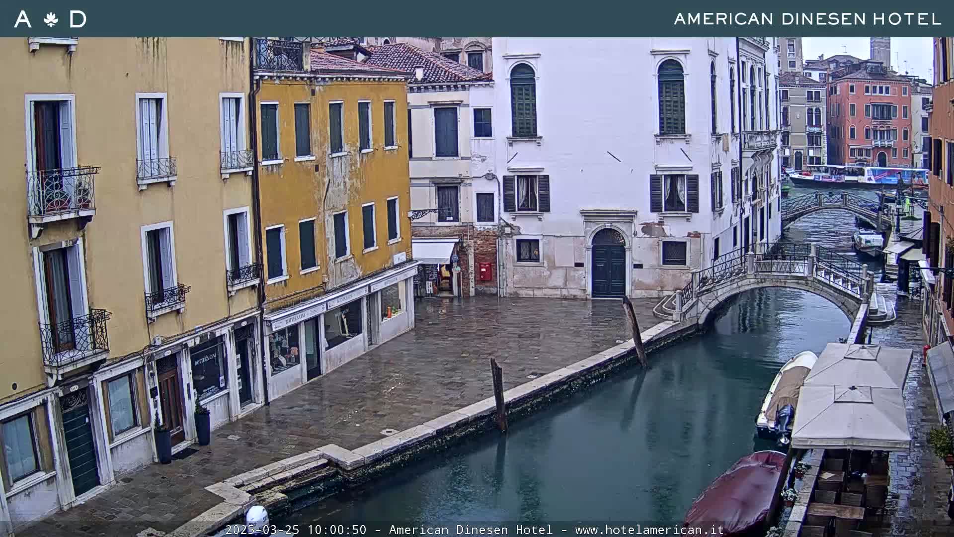 A view of a canal in Venice, Italy, showing several buildings lining the waterway on a wet, overcast day.